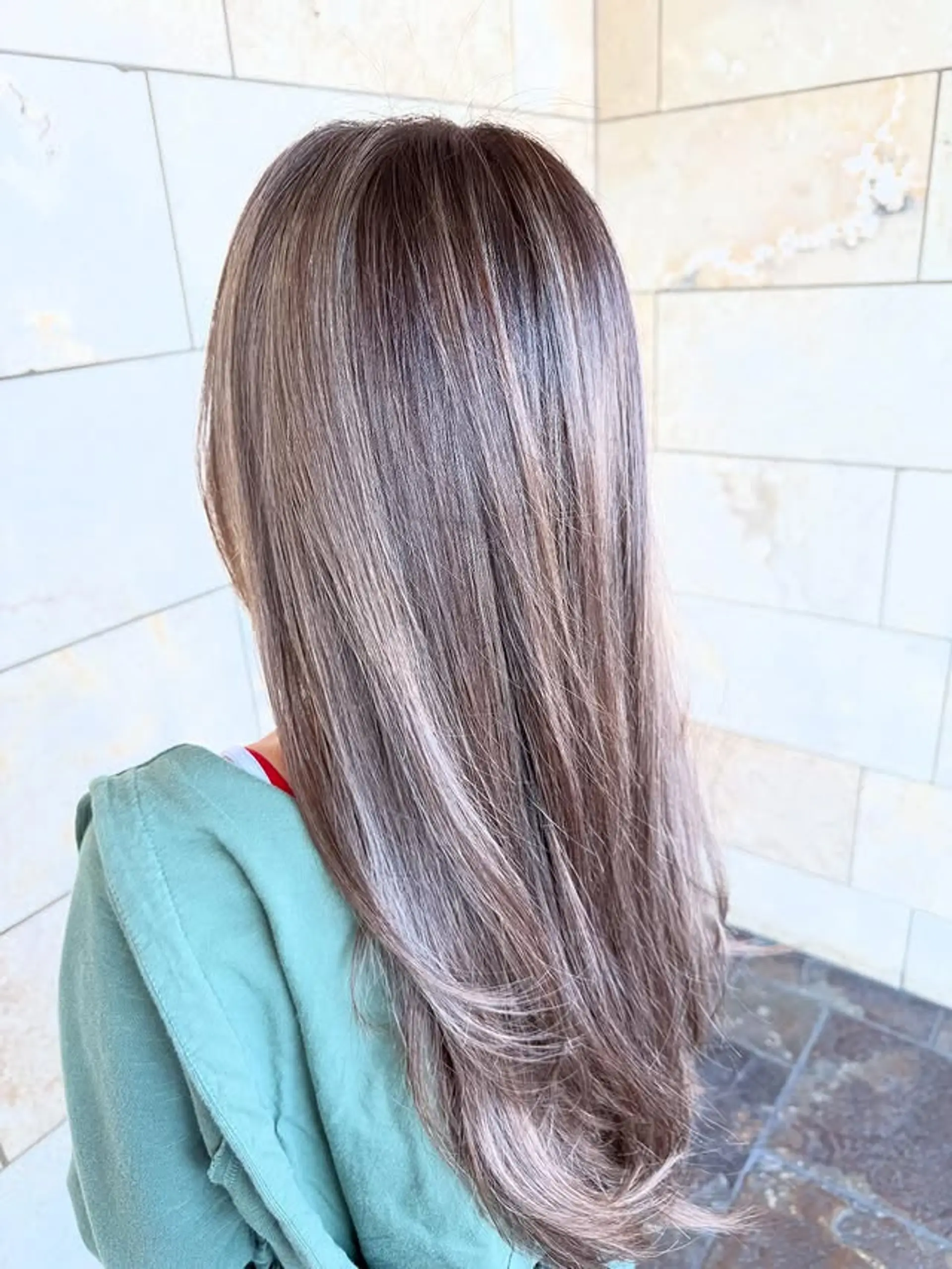 A long, layered hairstyle with a subtle ash blonde balayage. 1