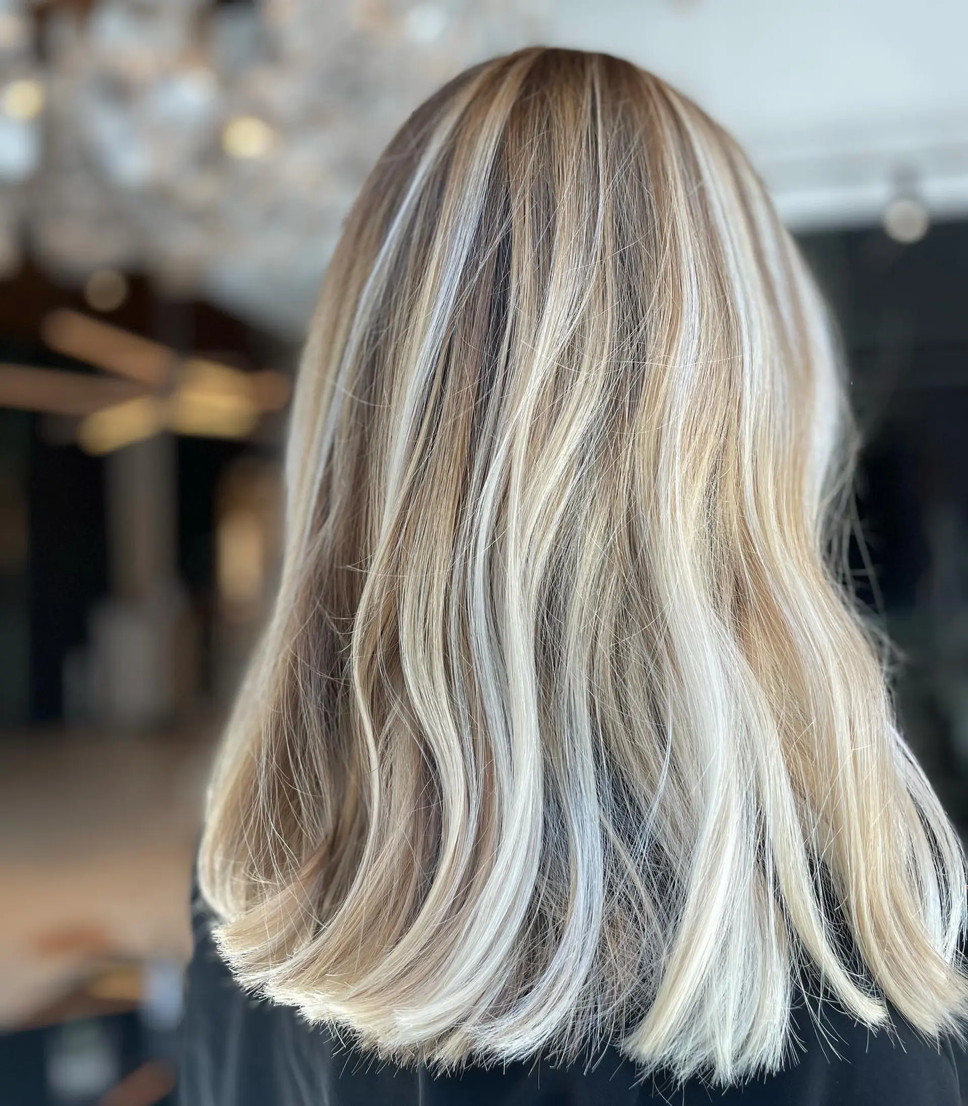 Medium-length dimensional blonde hair with high-contrast platinum highlights and a soft wave. 1