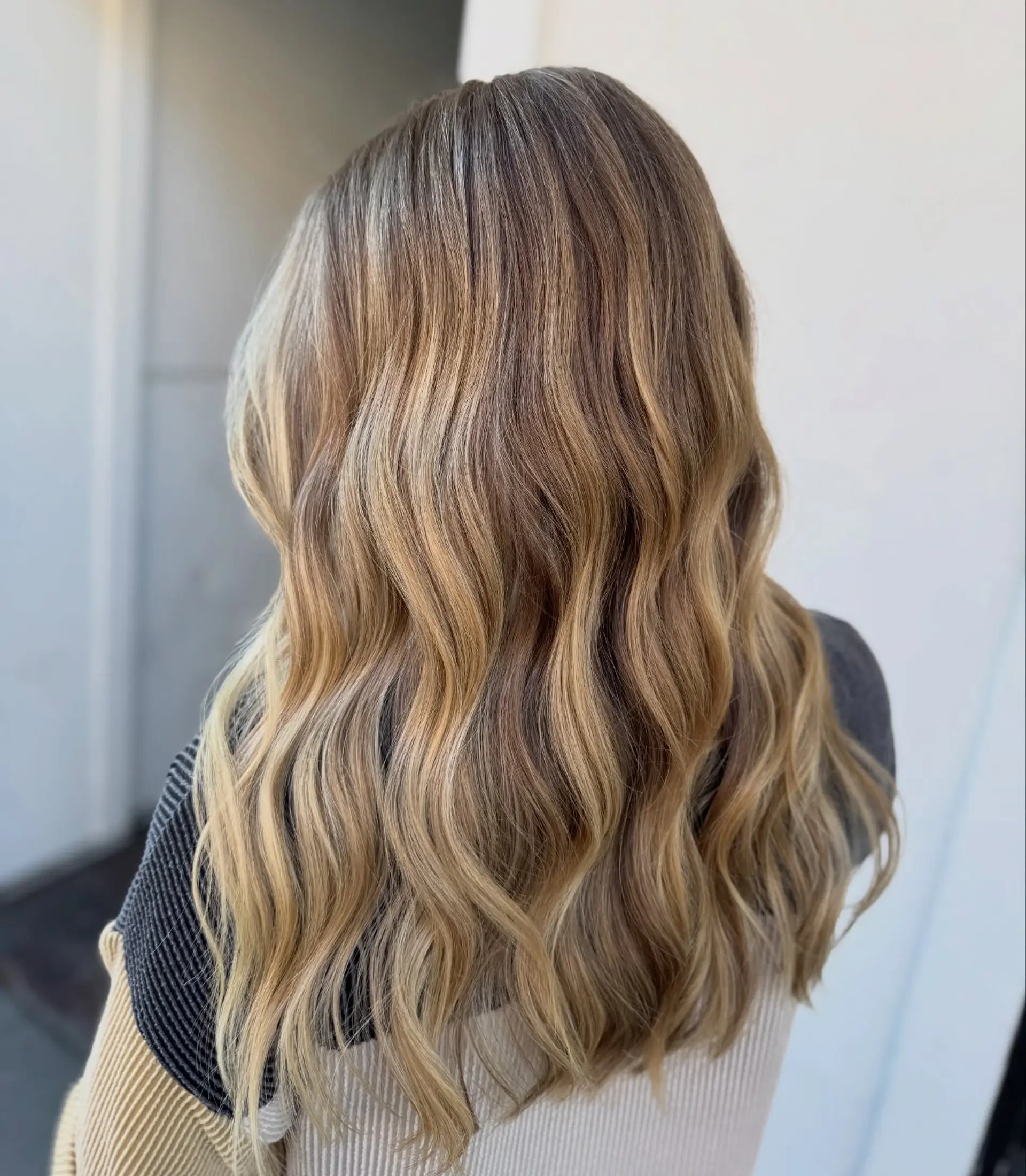 Long hair featuring a seamless, blended blonde balayage with soft, loose waves. 1