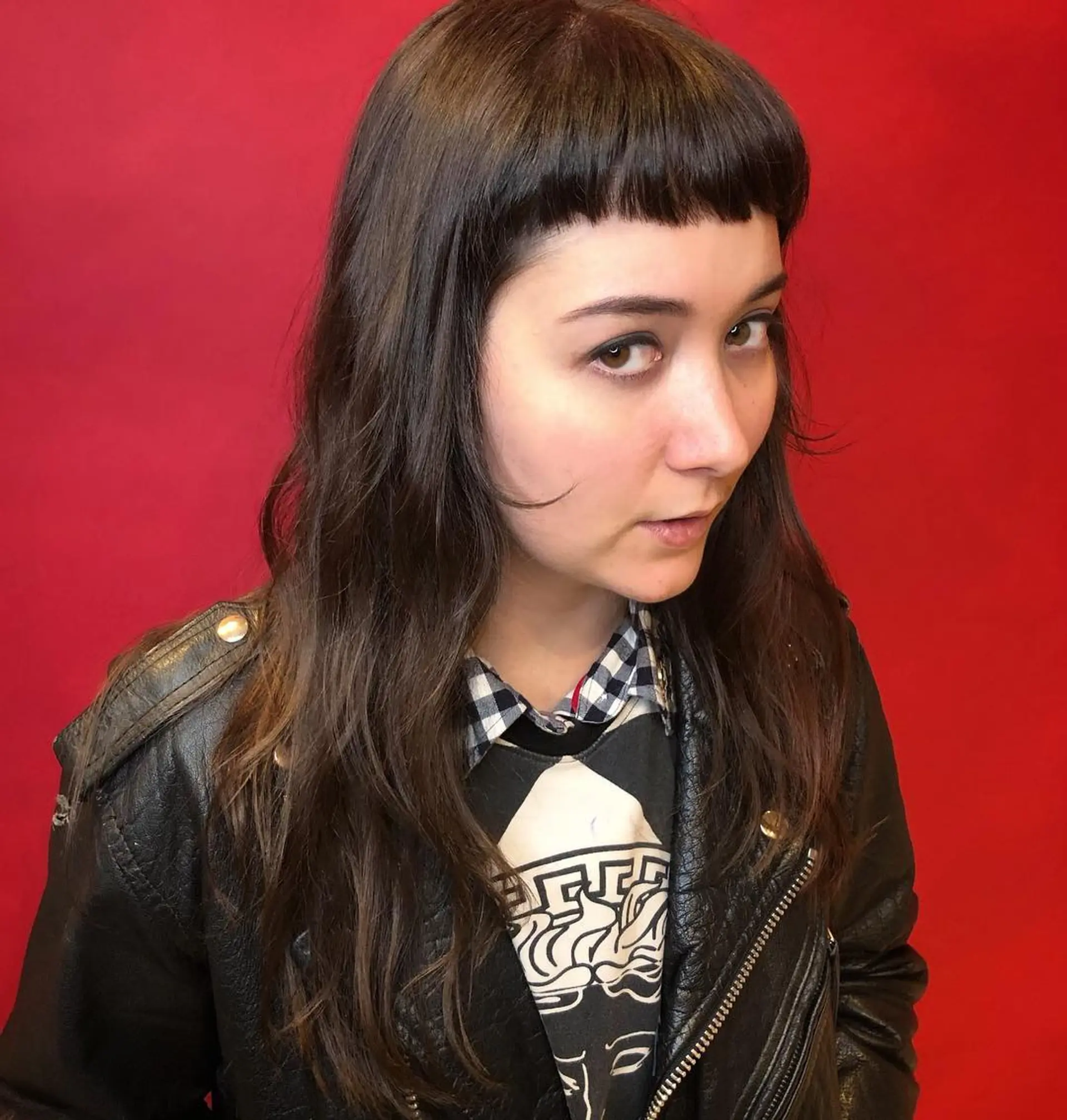 Long, wavy dark brown hair with blunt bangs and layered waves, creating a modern and edgy style. 1