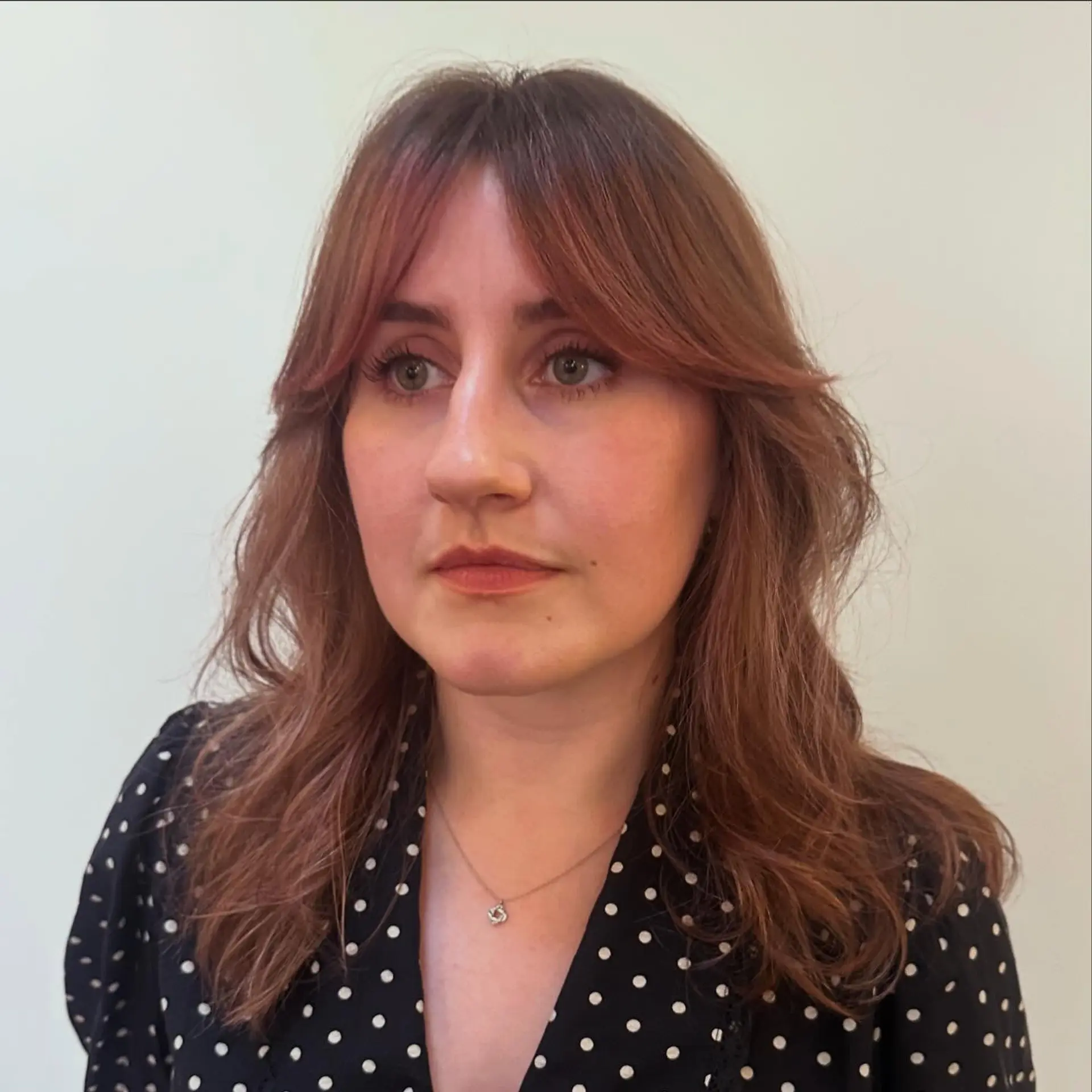 Medium-length layered wavy hair with curtain bangs and subtle dusty pink tones. 1