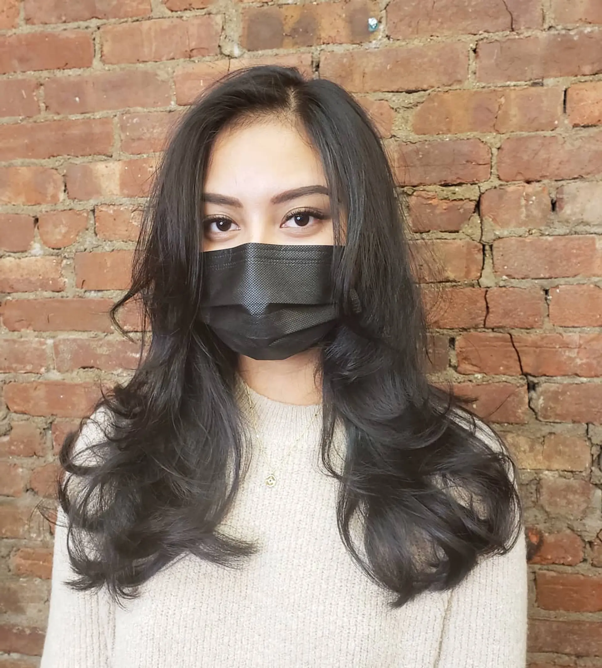 Long layered dark hair styled with face-framing layers and soft, voluminous blowout curls at the ends. 1