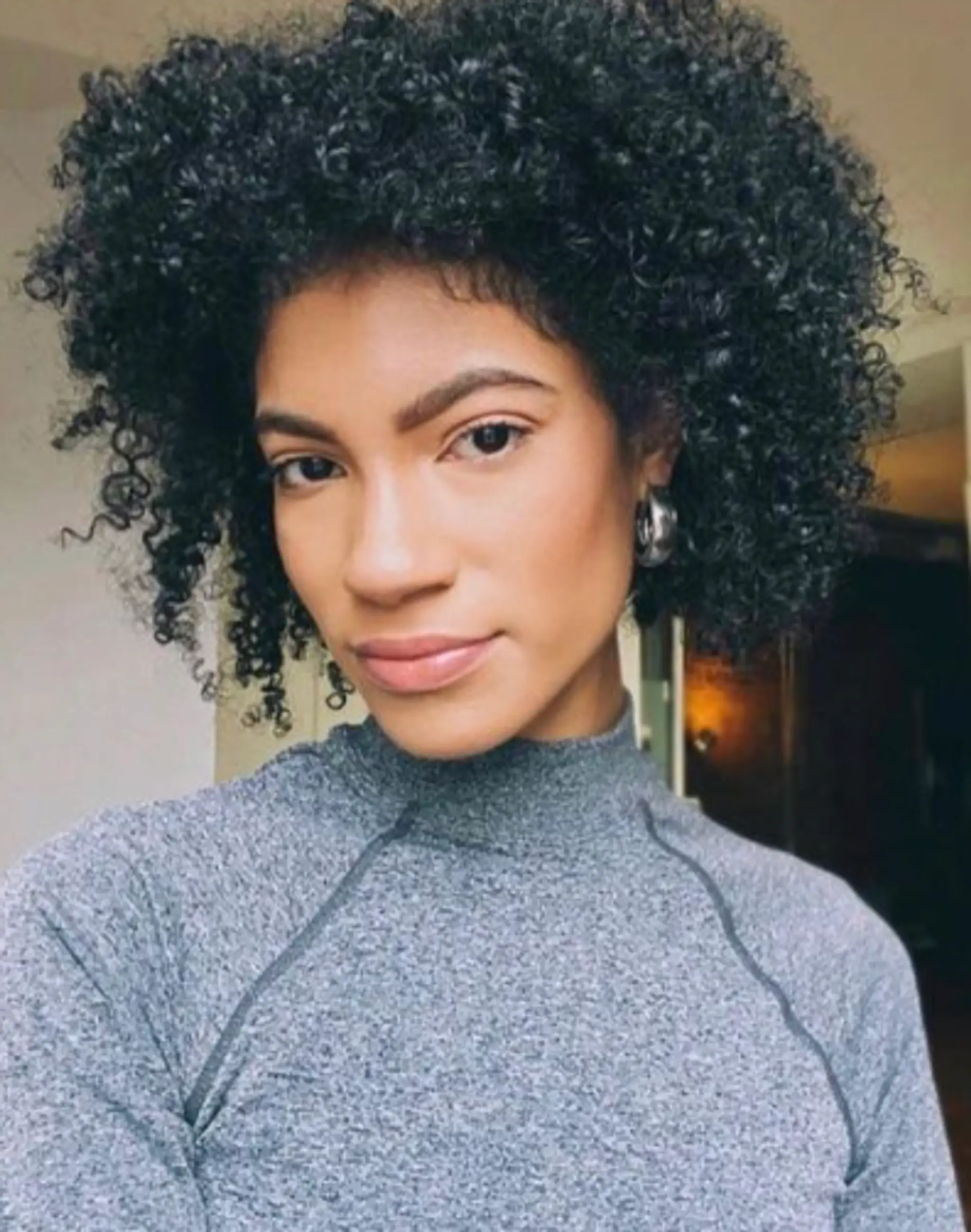 A short, voluminous curly style with dark highlights, emphasizing the natural coily texture.