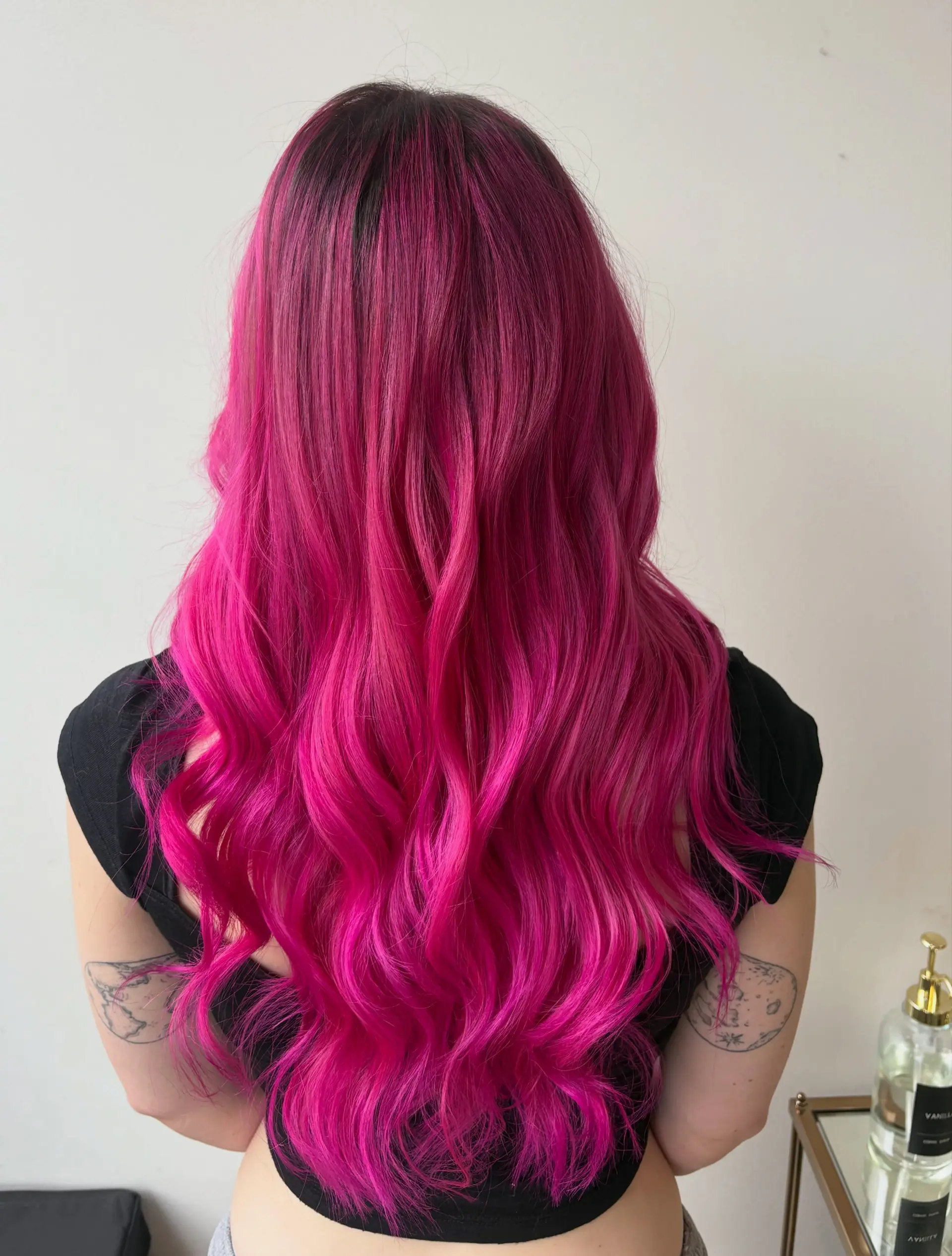 Vibrant hot pink long hair with a subtle dark shadow root, styled into soft textured waves. 1
