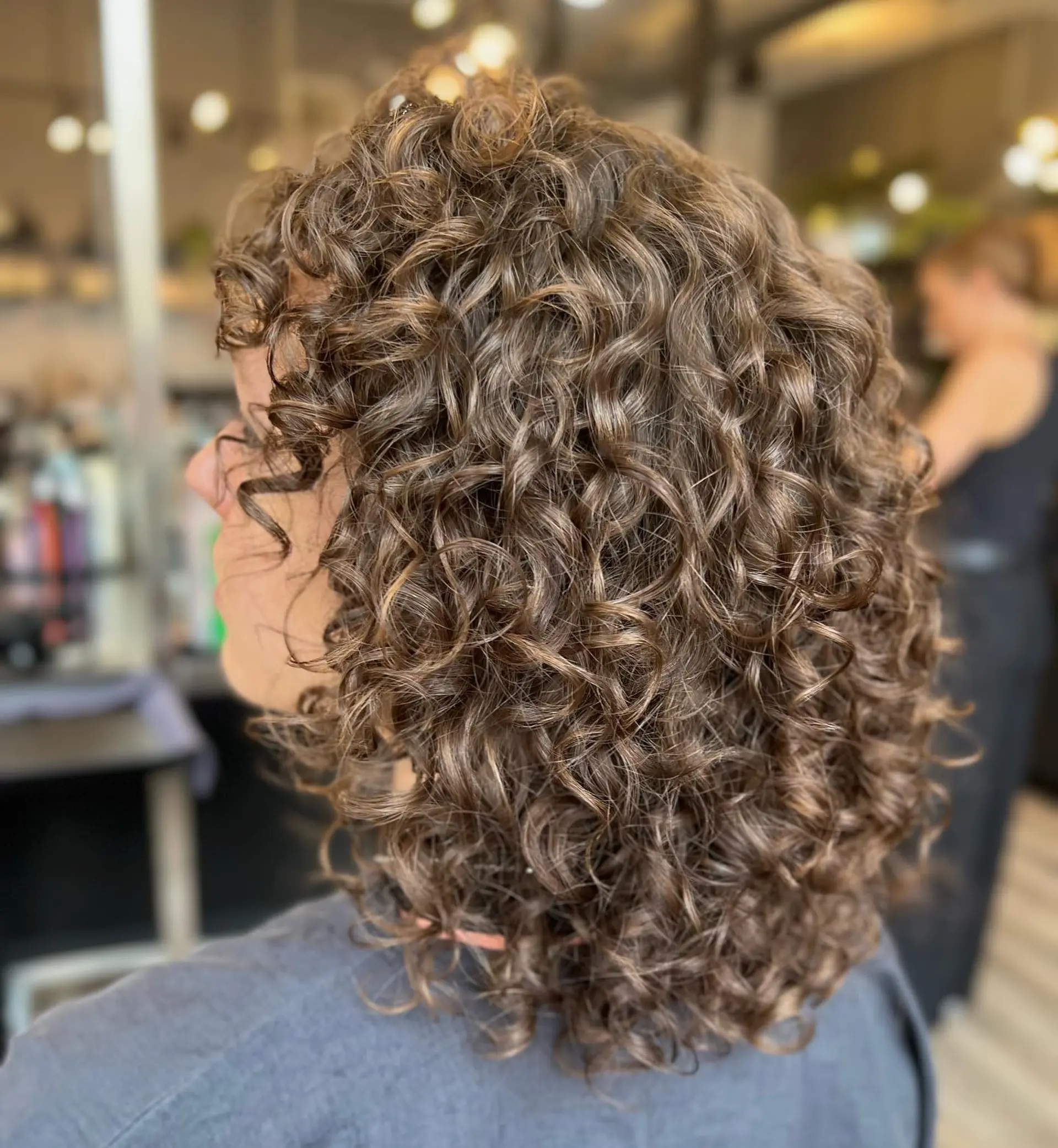 A curly shag haircut with layered curls and dimensional color. 1