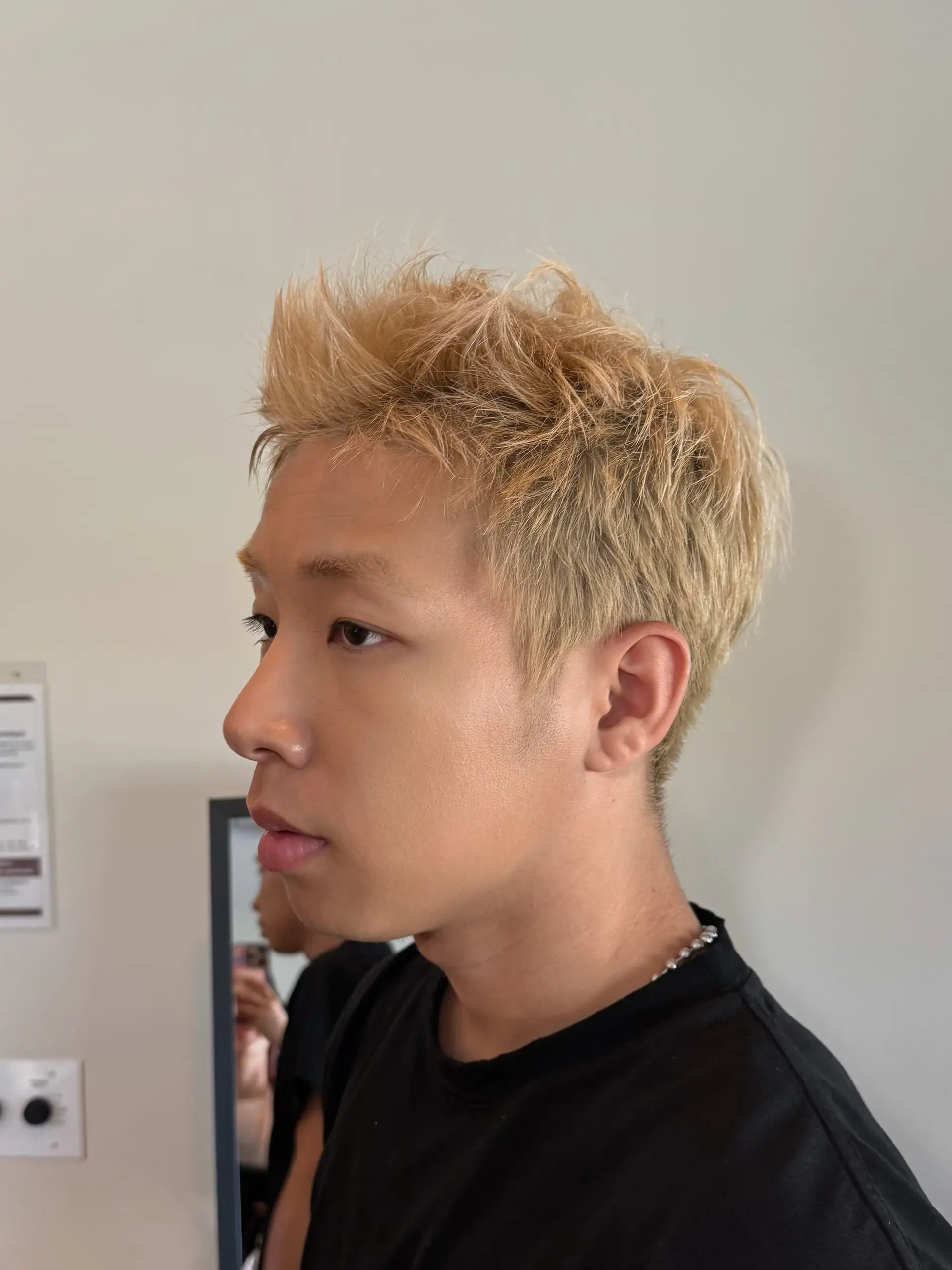 A short, bleach blonde haircut styled with textured, piecey spikes swept upward in the front and neatly tapered along the sides. 1