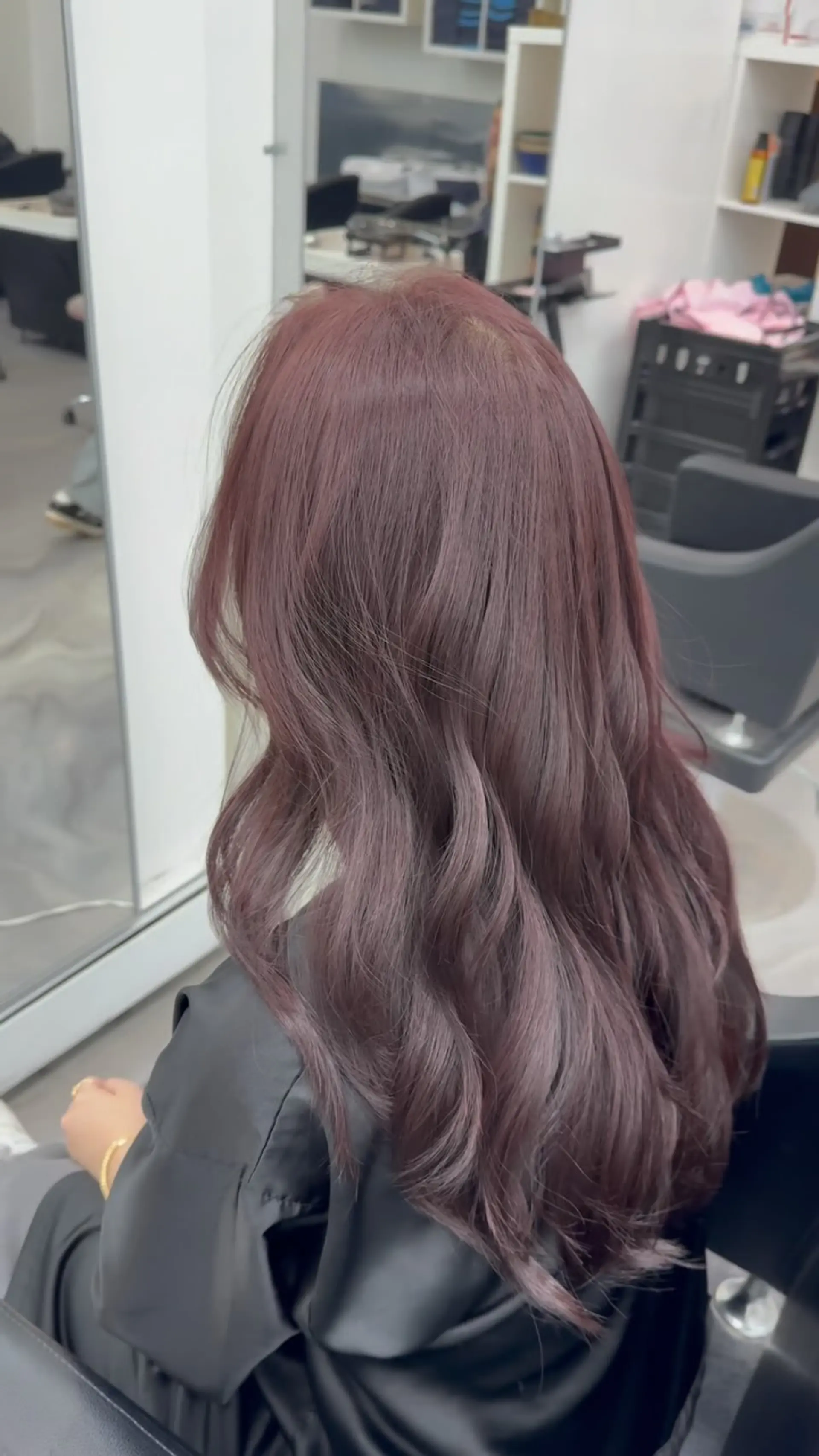 Long layered hair styled with soft, voluminous waves in a muted smoky mauve hue. 1