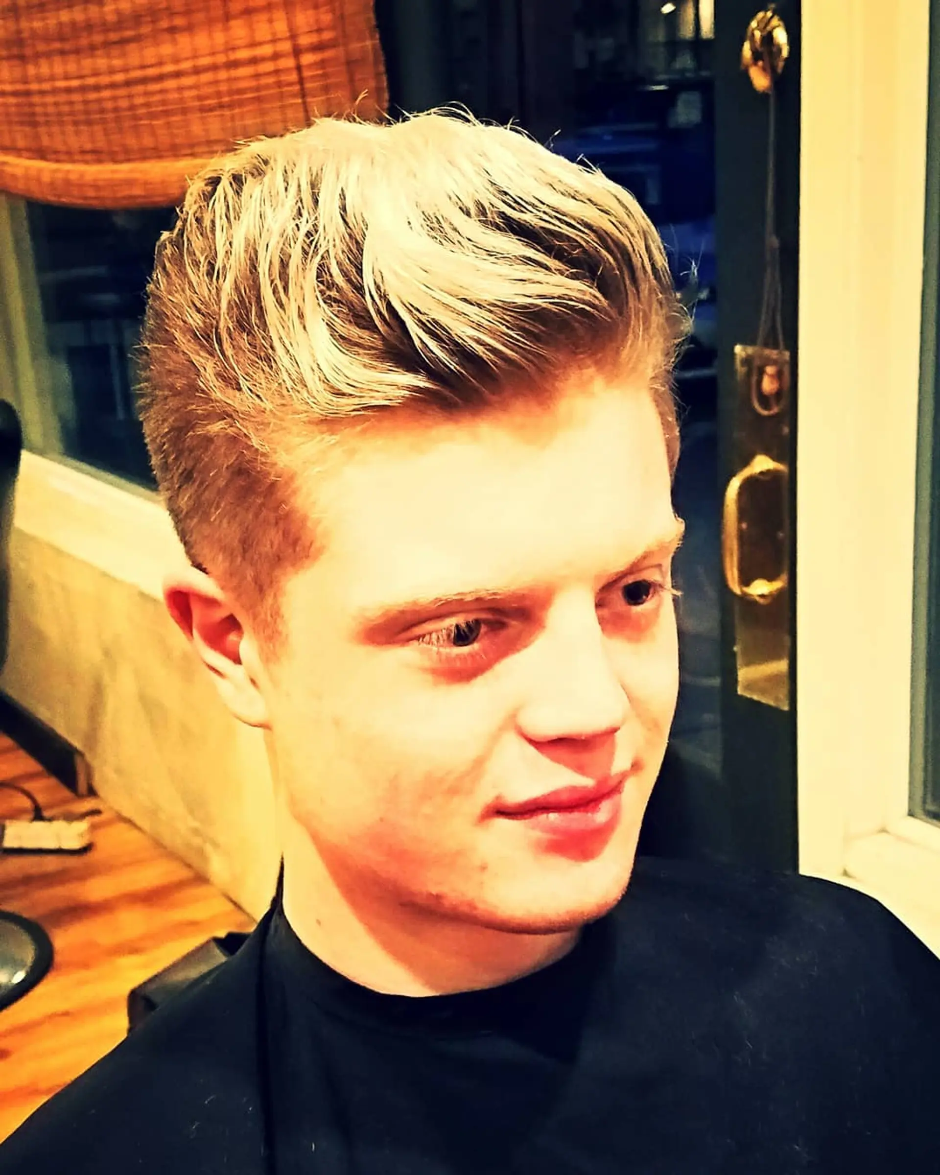 A men's short haircut styled into a textured, swept-up quiff with tapered sides. 1