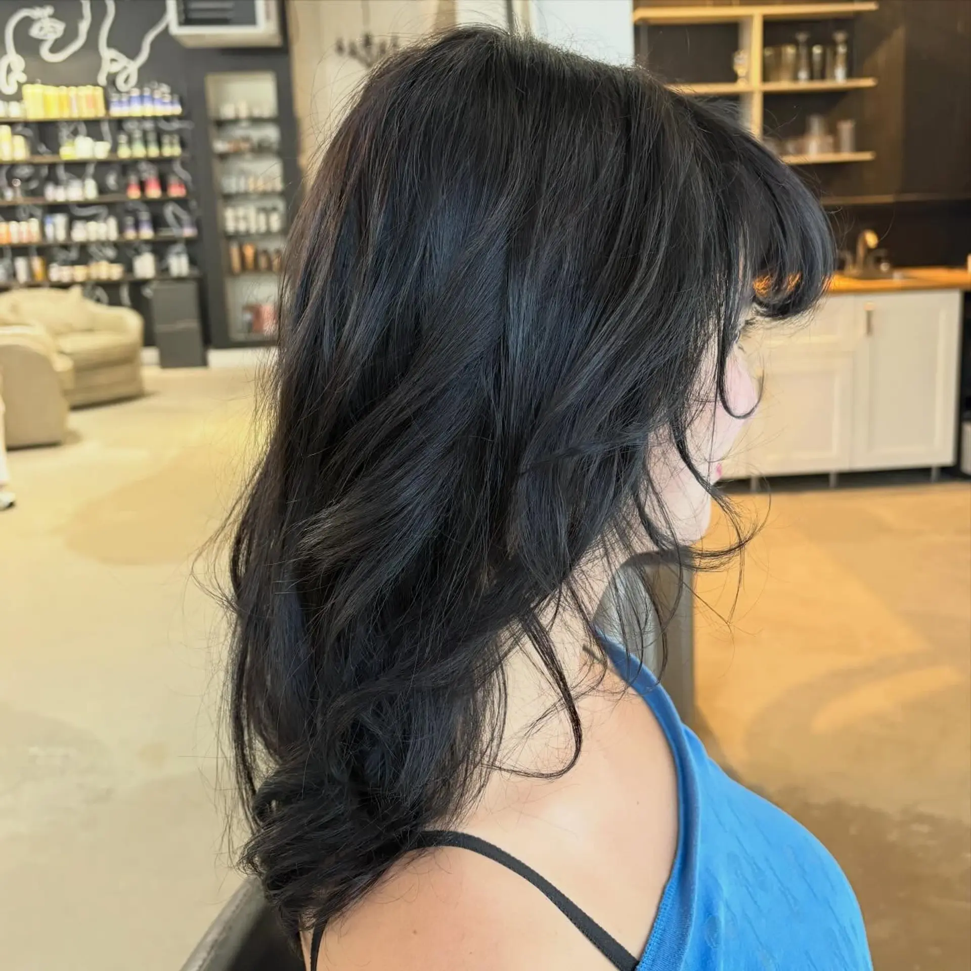 Medium-length dark layered hair styled in a voluminous blowout with soft waves and face-framing fringe. 1
