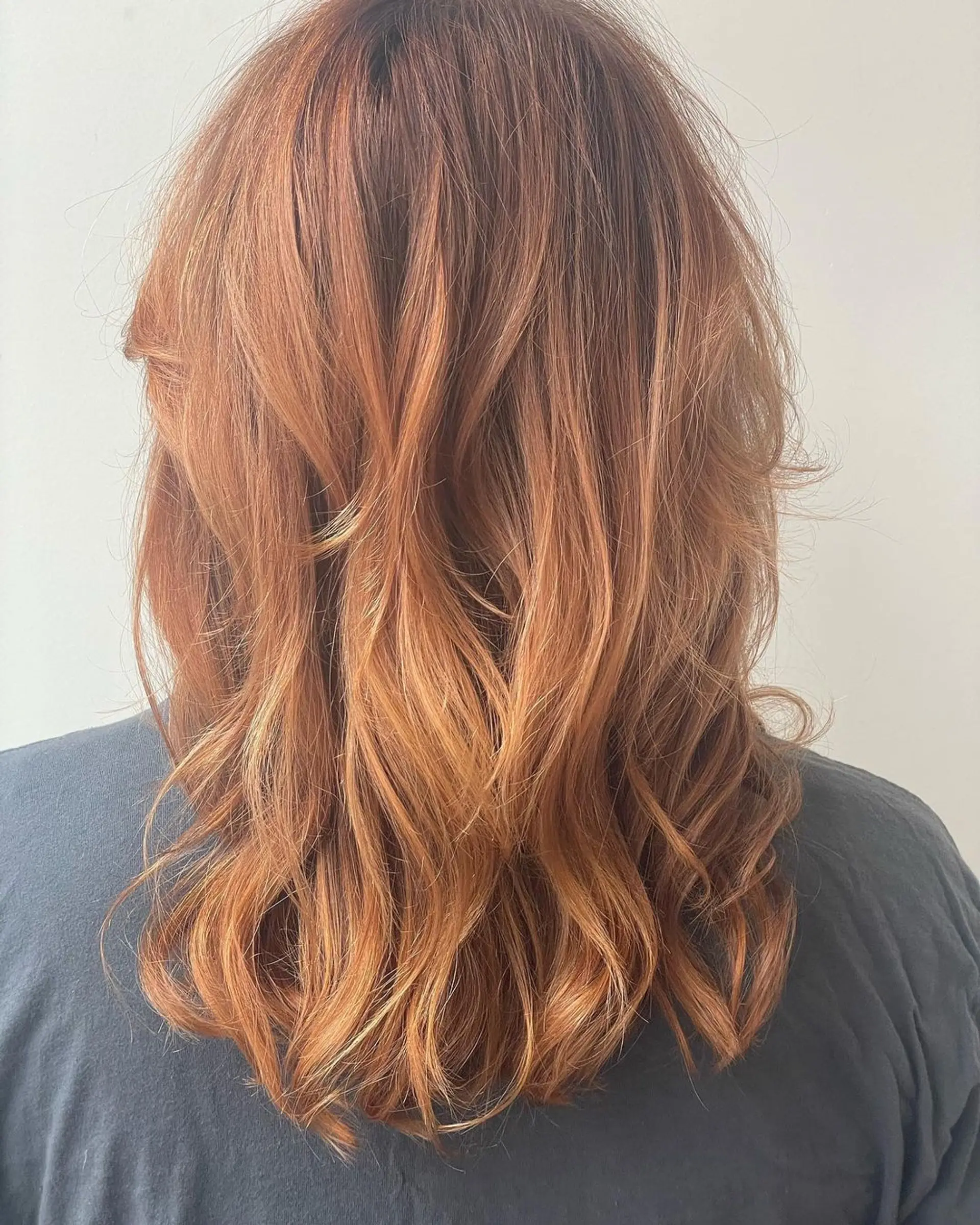 Medium-length, wavy hairstyle in a copper shade, featuring soft waves, long bangs, and a layered, face-framing cut. 3