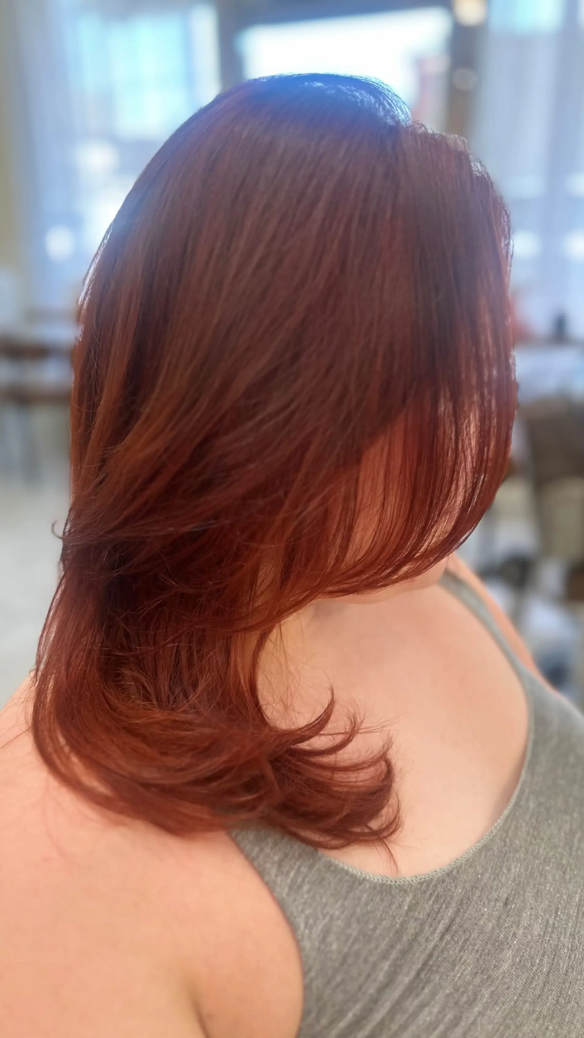 Medium-length vibrant auburn copper hair styled with soft, face-framing layers and flipped ends. 1