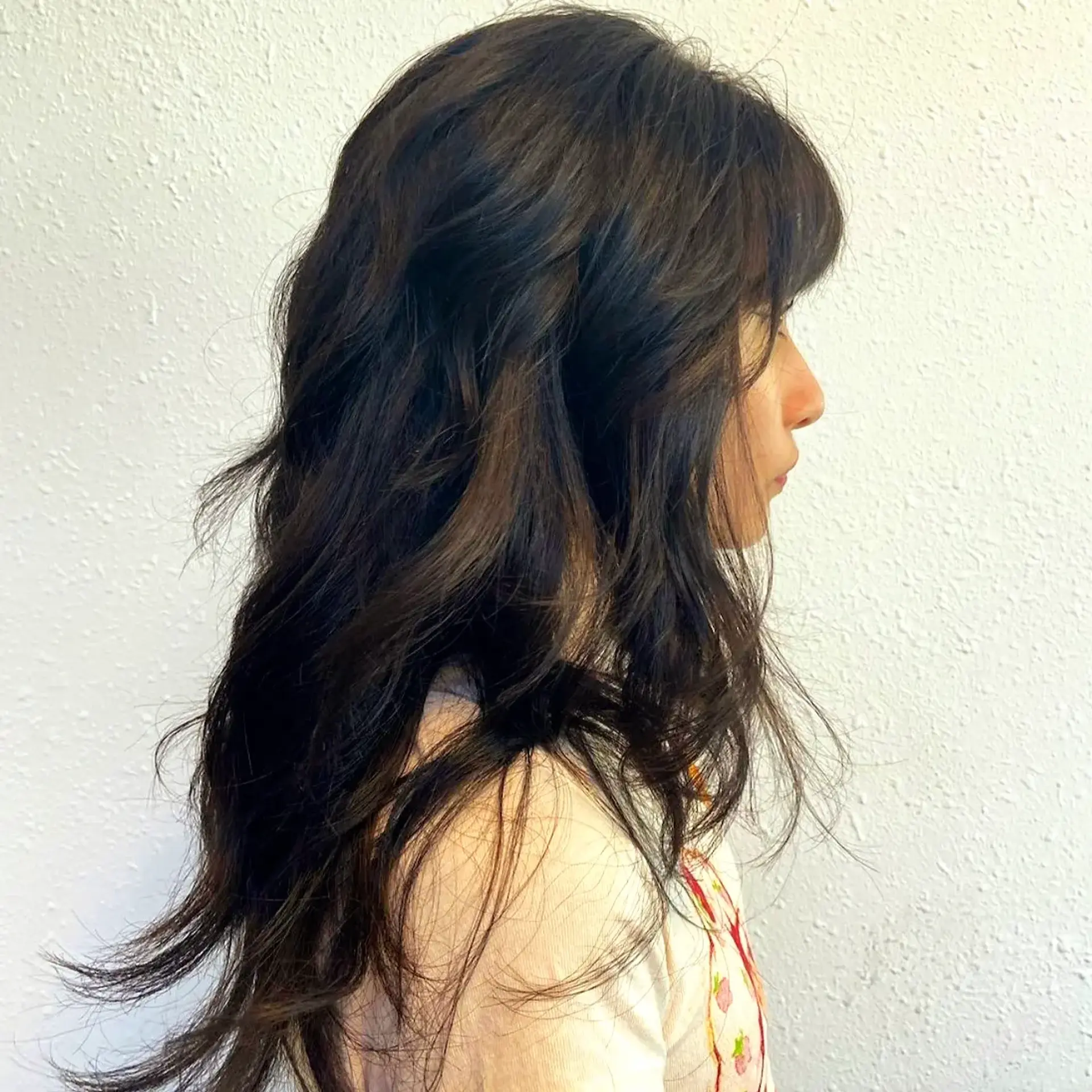 A modern long shag haircut featuring face-framing fringe, feathered crown layers, and effortless tousled waves. 1