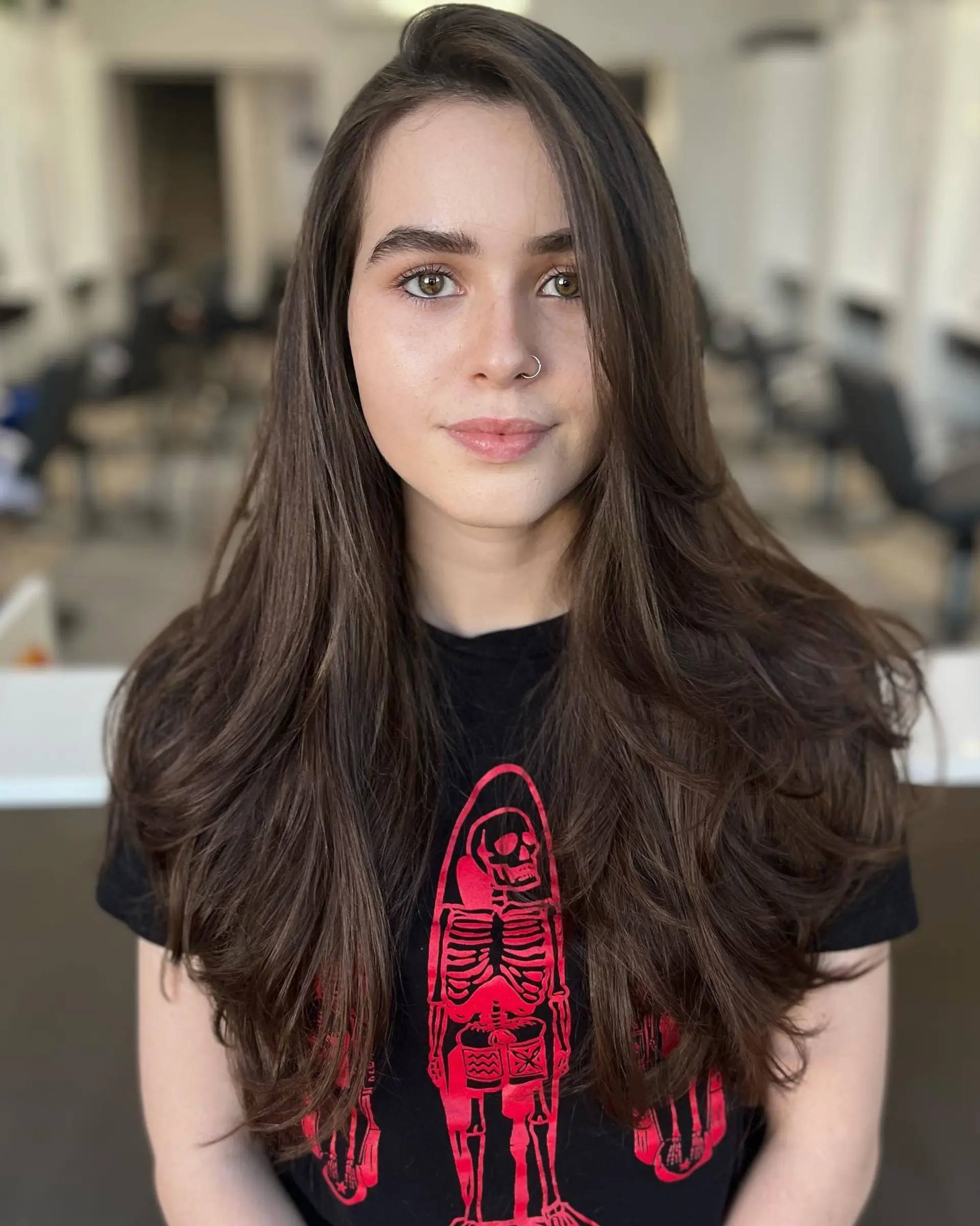 Long, rich dark brown hair cut with soft, face-framing layers and styled with a voluminous round-brush blowout. 1