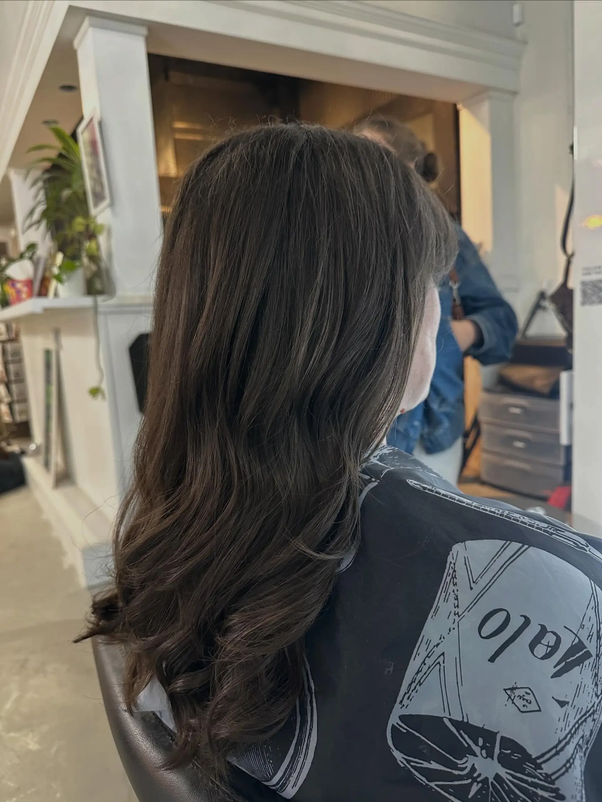 Long dark brown hair styled in a smooth blowout with soft, loose waves and curled ends. 1