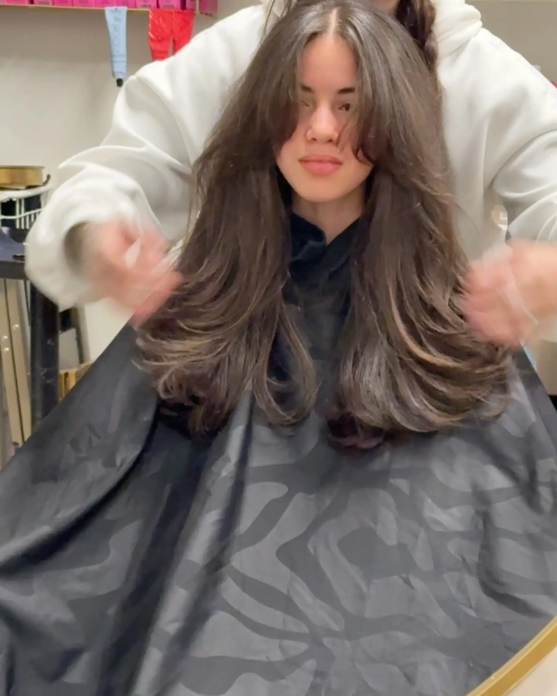 Voluminous long layered haircut styled into a bouncy blowout with face-framing curtain bangs. 1