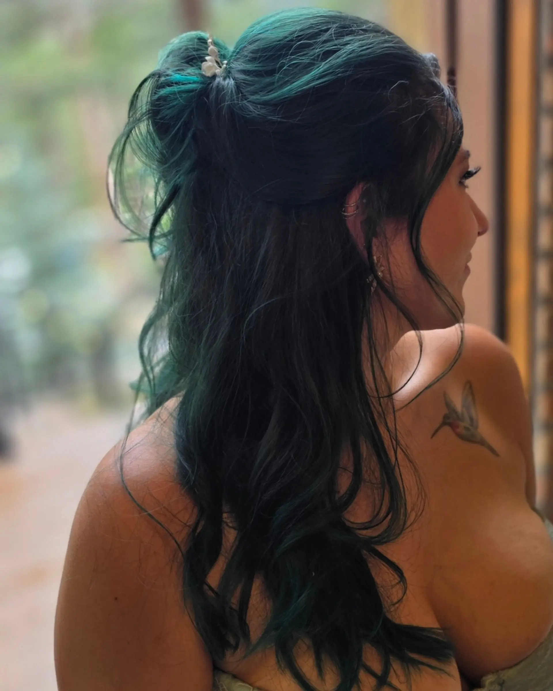 A romantic half-up half-down hairstyle featuring voluminous dark emerald teal waves accented with a delicate pearl hairpiece. 1