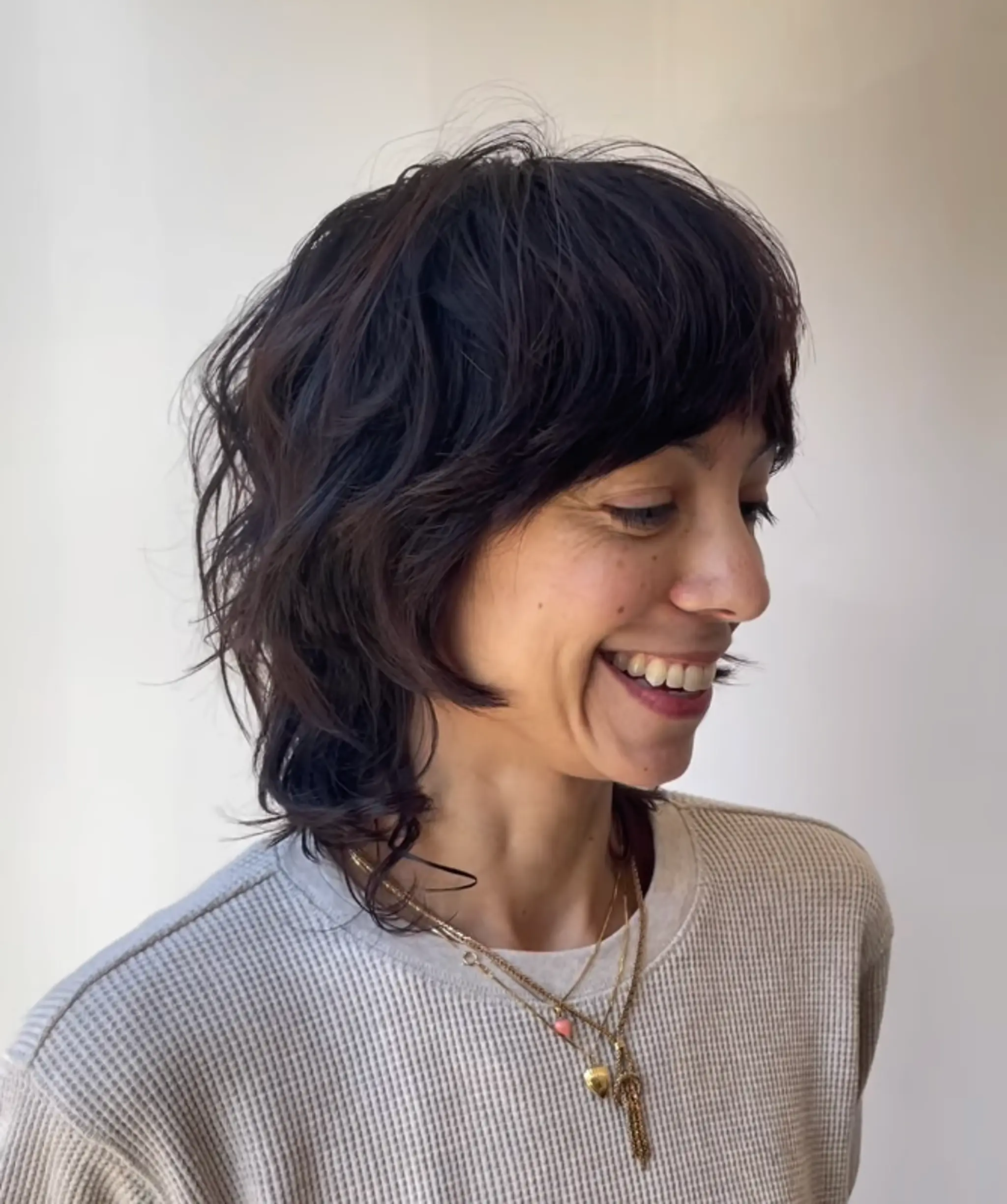 Medium-length, dark brown wavy hair with shaggy layers and side-swept bangs, creating an effortless, textured look. 2