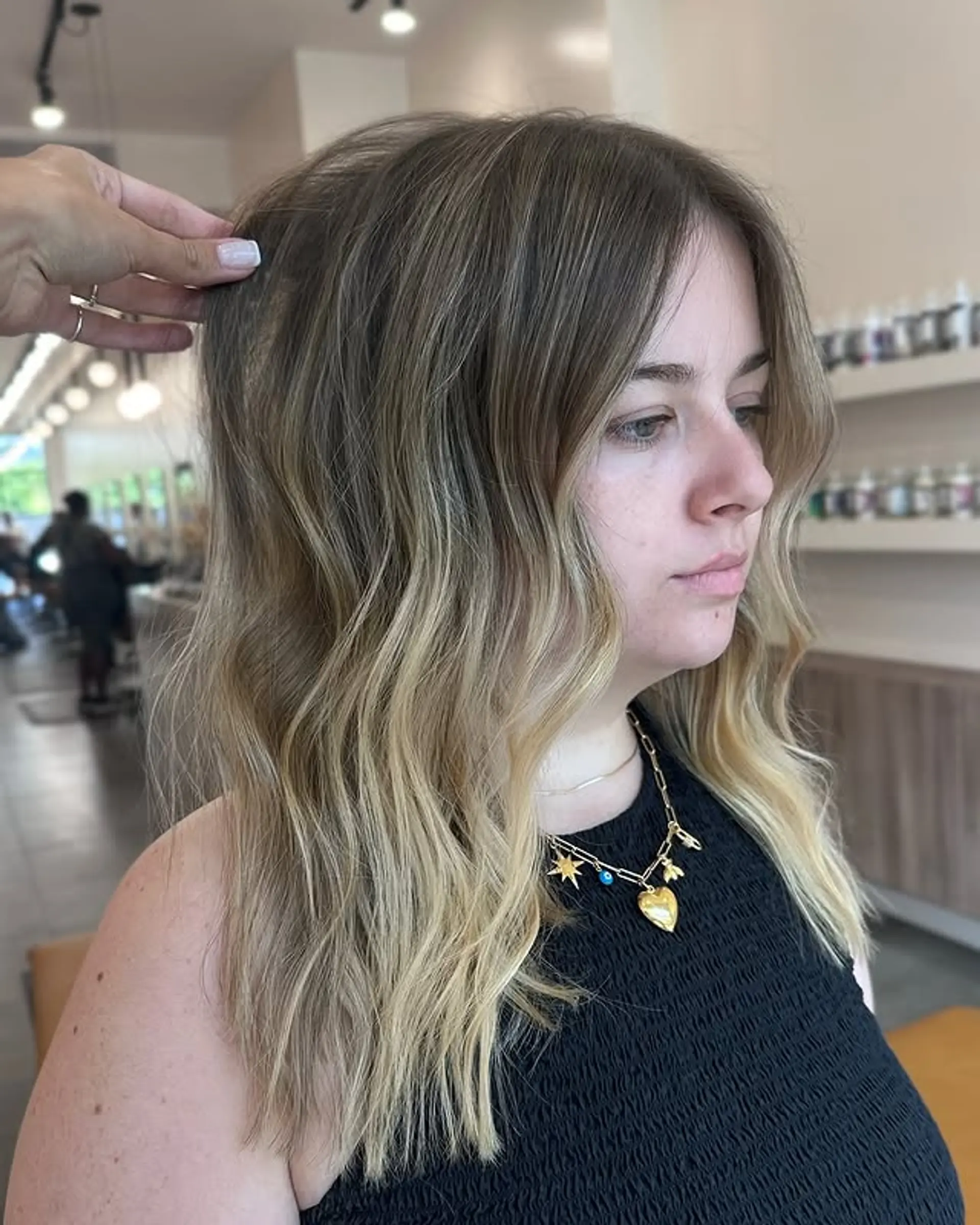 A sombre hairstyle with soft, beachy waves and a seamless blend of brown roots into blonde ends. 1