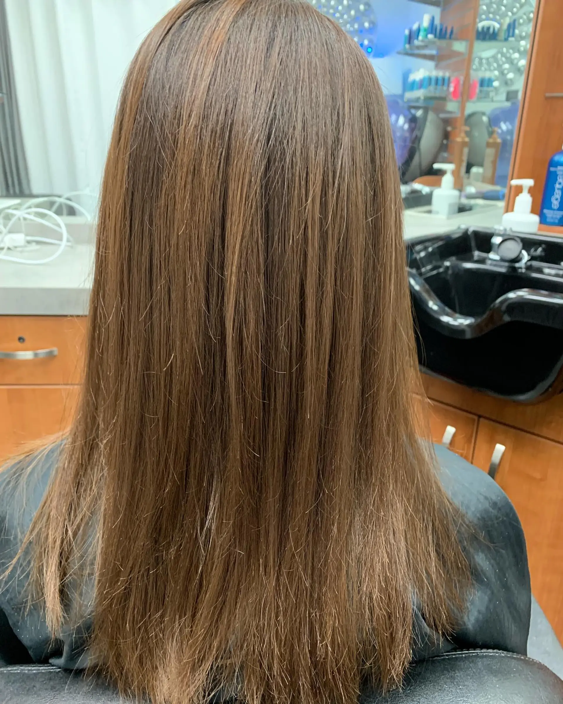Straight, smooth mid-back length hair treated with a smoothing treatment for a sleek, frizz-free finish. 1