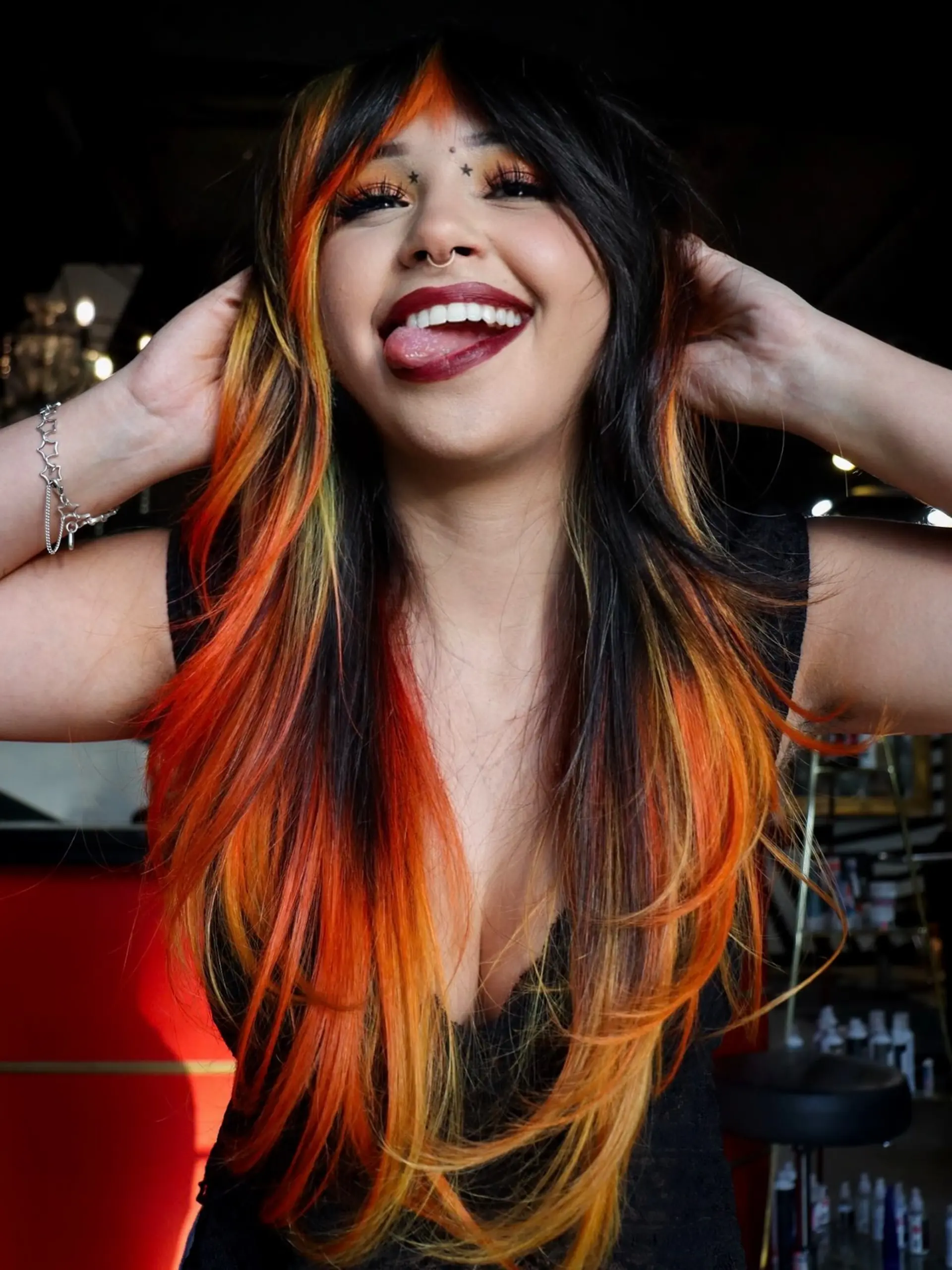 Long layered dark hair accented with vibrant fiery orange and yellow tipped layers and face-framing fringe. 1