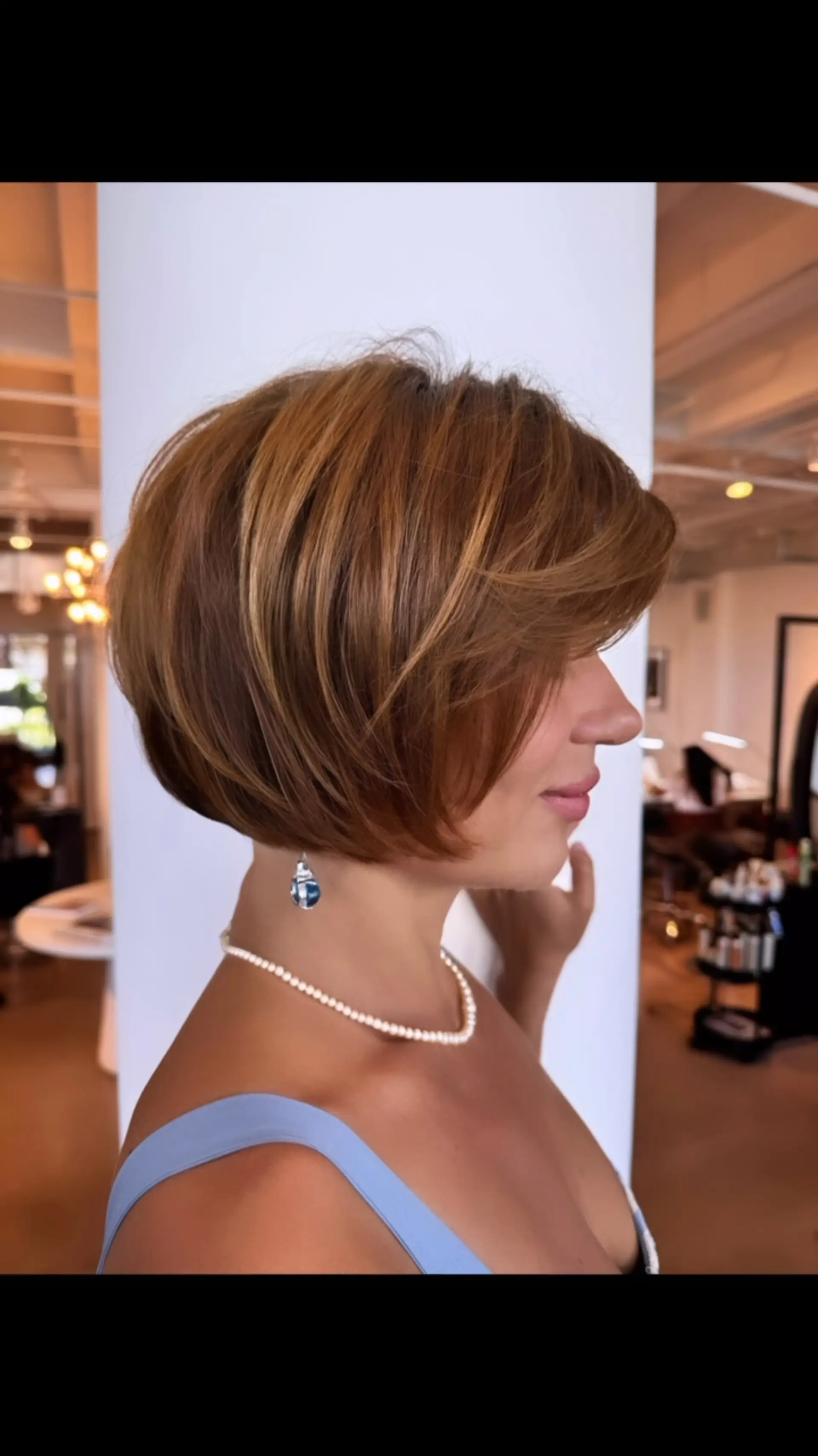 A rounded, voluminous chin-length bob haircut with feathered layers and side-swept framing in warm caramel-brown tones. 1