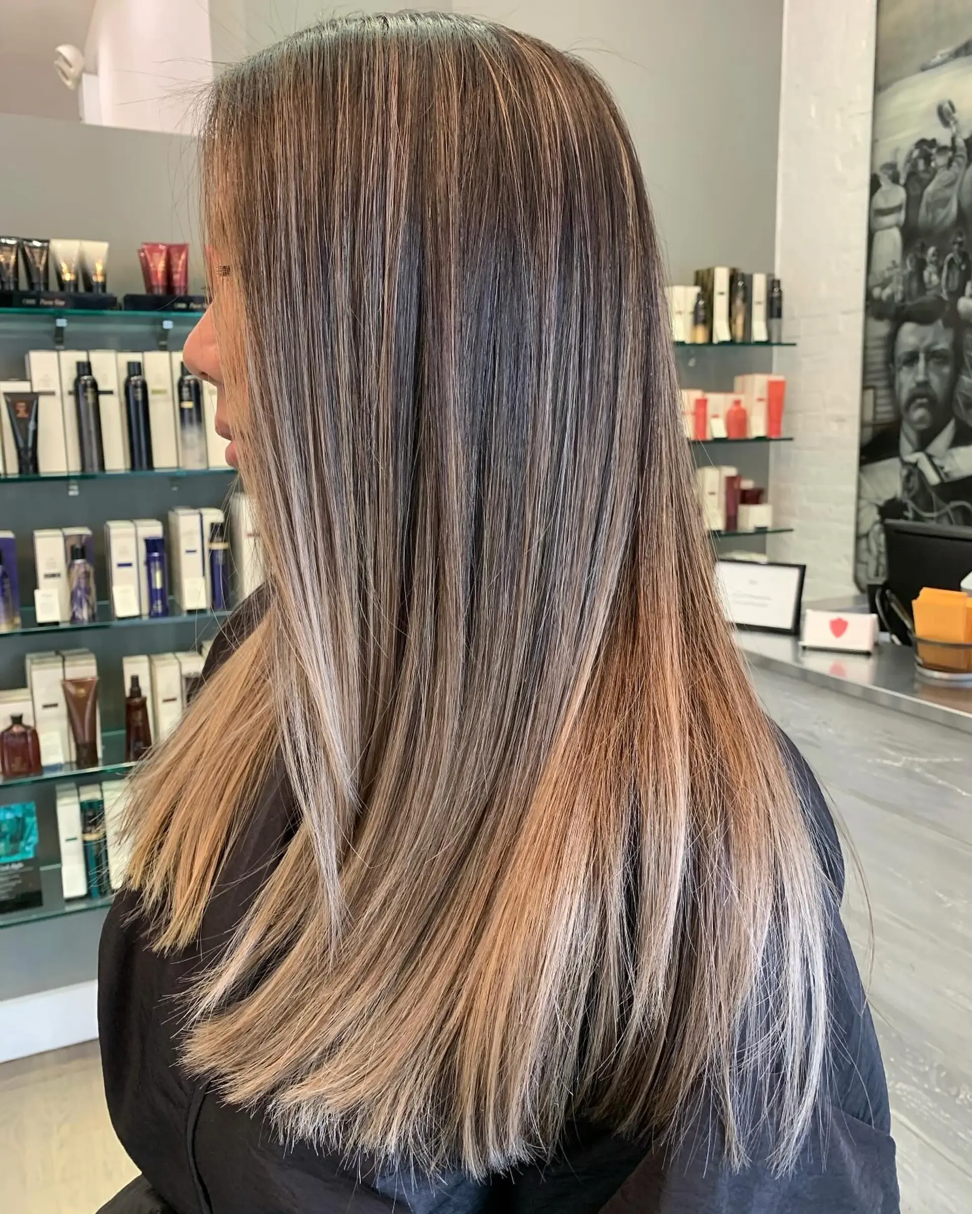 Long, sleek straight hair enhanced with fine dimensional blonde and caramel babylights throughout a brunette base. 1