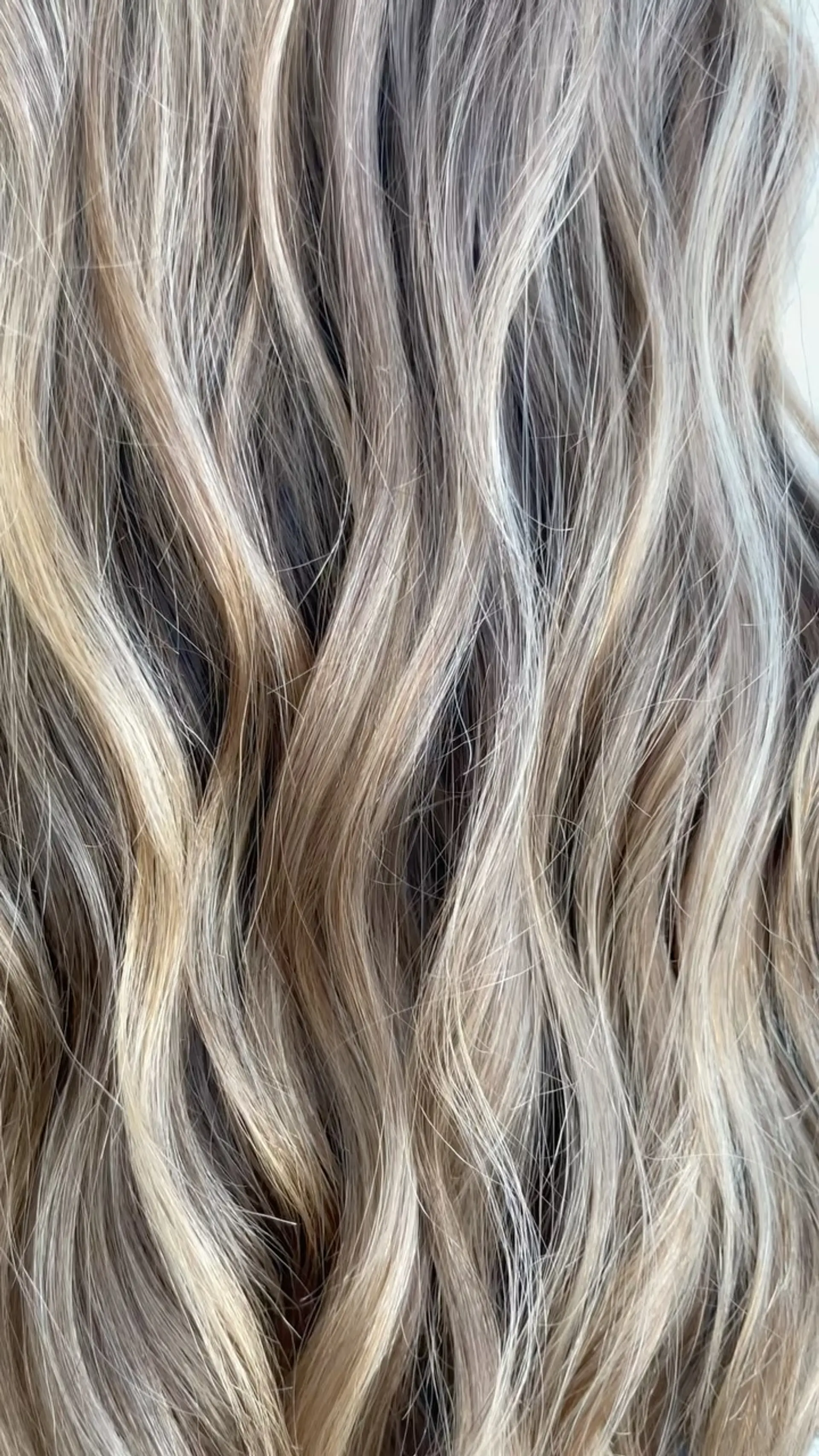 Dimensional blend of cool ash and golden beige blonde balayage styled into relaxed, fluid waves. 1