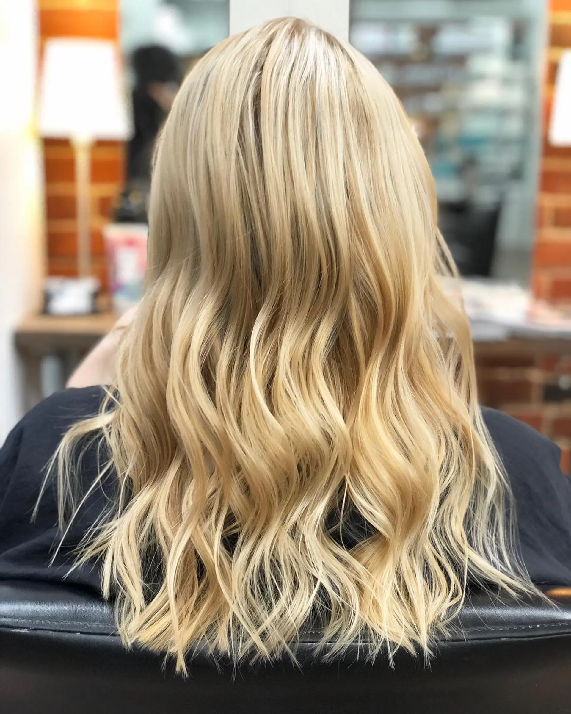 A long layered haircut styled in soft, loose waves with bright dimensional blonde highlights. 1
