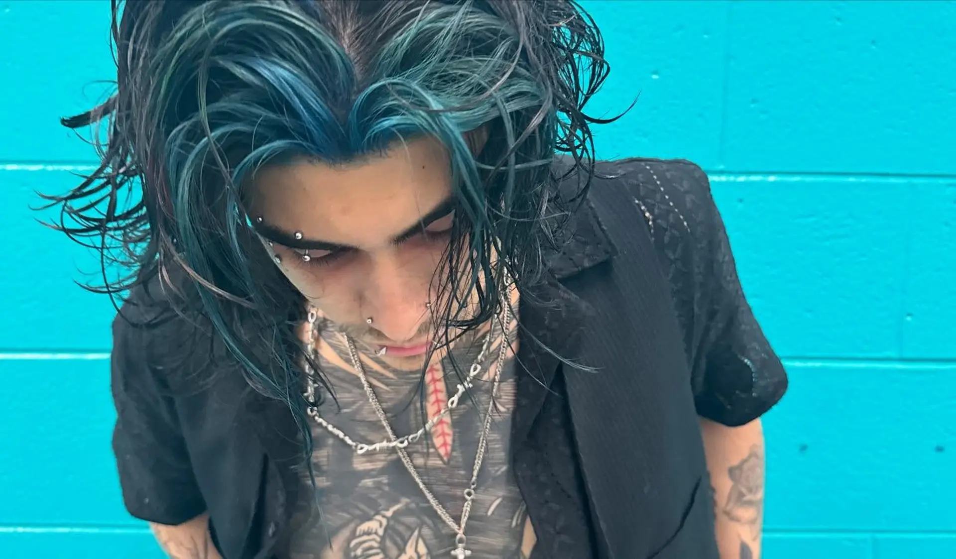 Medium-length dark hair styled with textured, piecey waves and vibrant teal blue face-framing color. 1