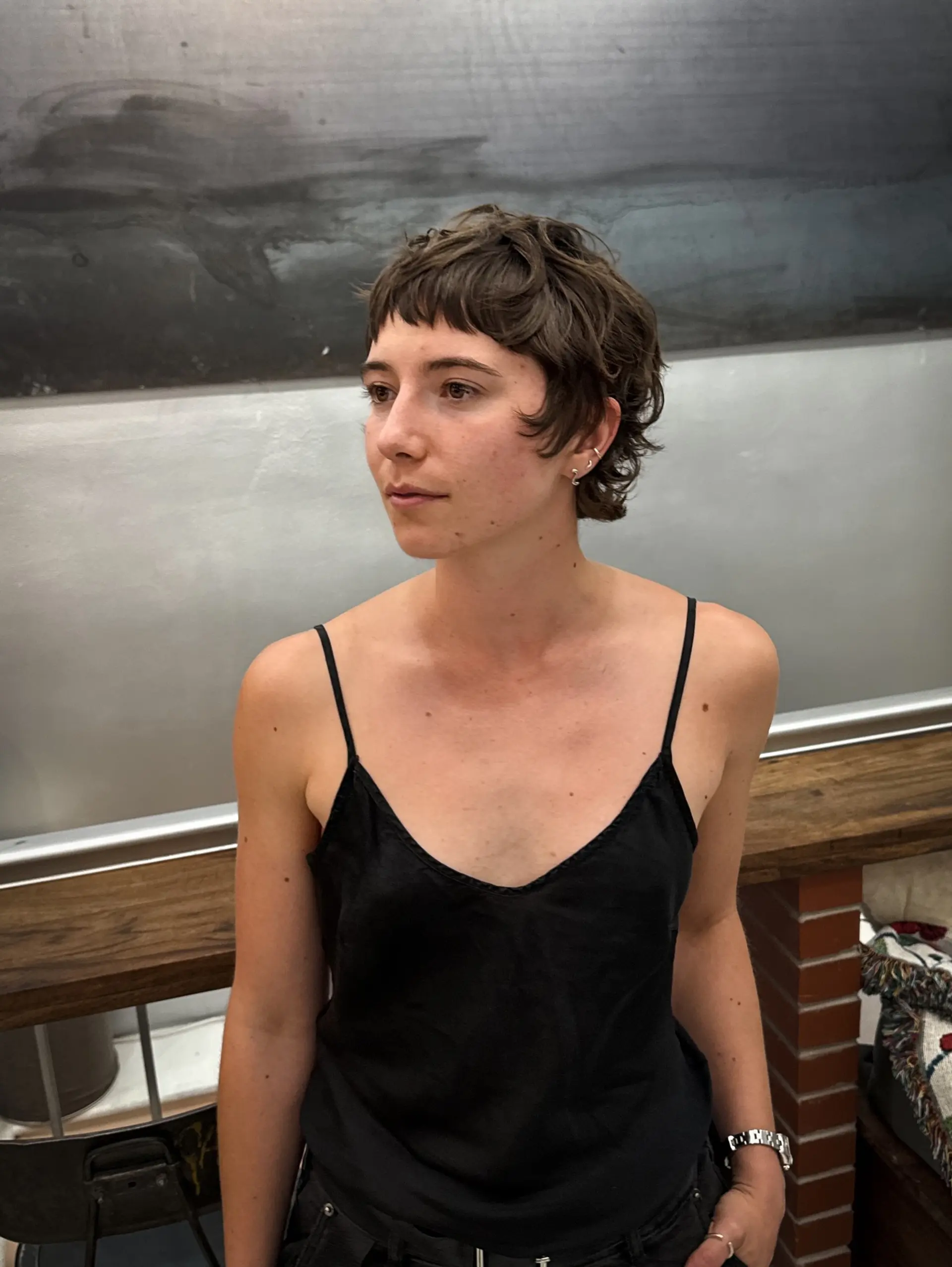A short, wavy shag haircut with choppy layers and very short, micro bangs. 2