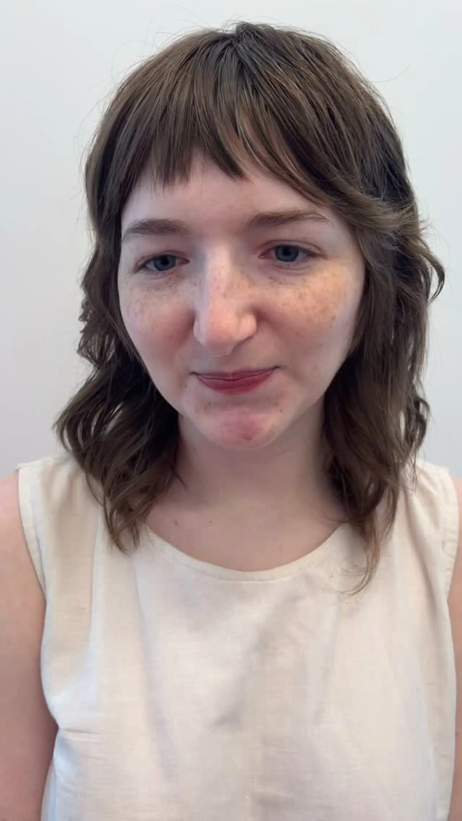A textured medium-length shag haircut with soft waves and short, choppy baby bangs. 1