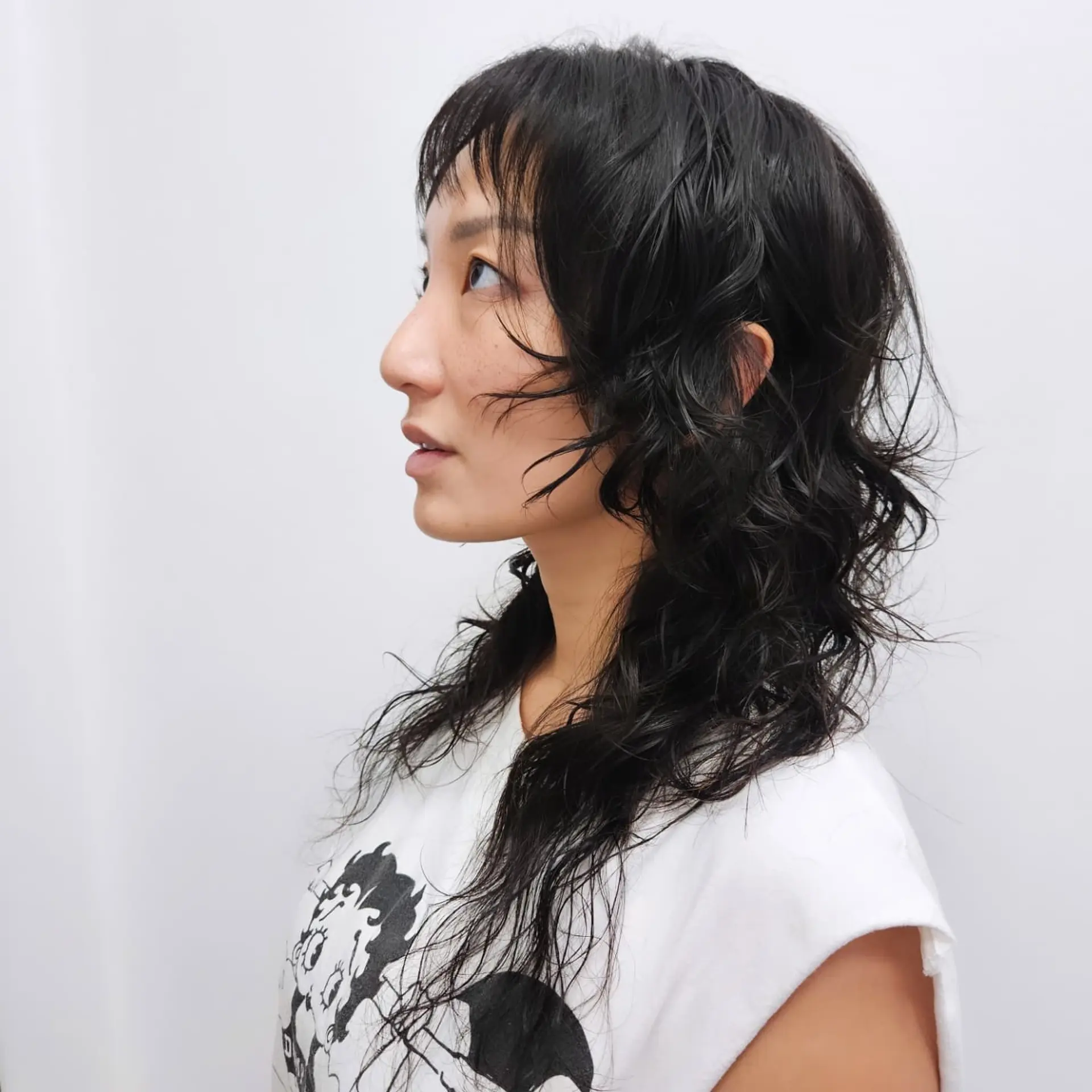A textured shaggy mullet featuring wispy micro bangs and piecey, soft waves that taper toward the ends. 1