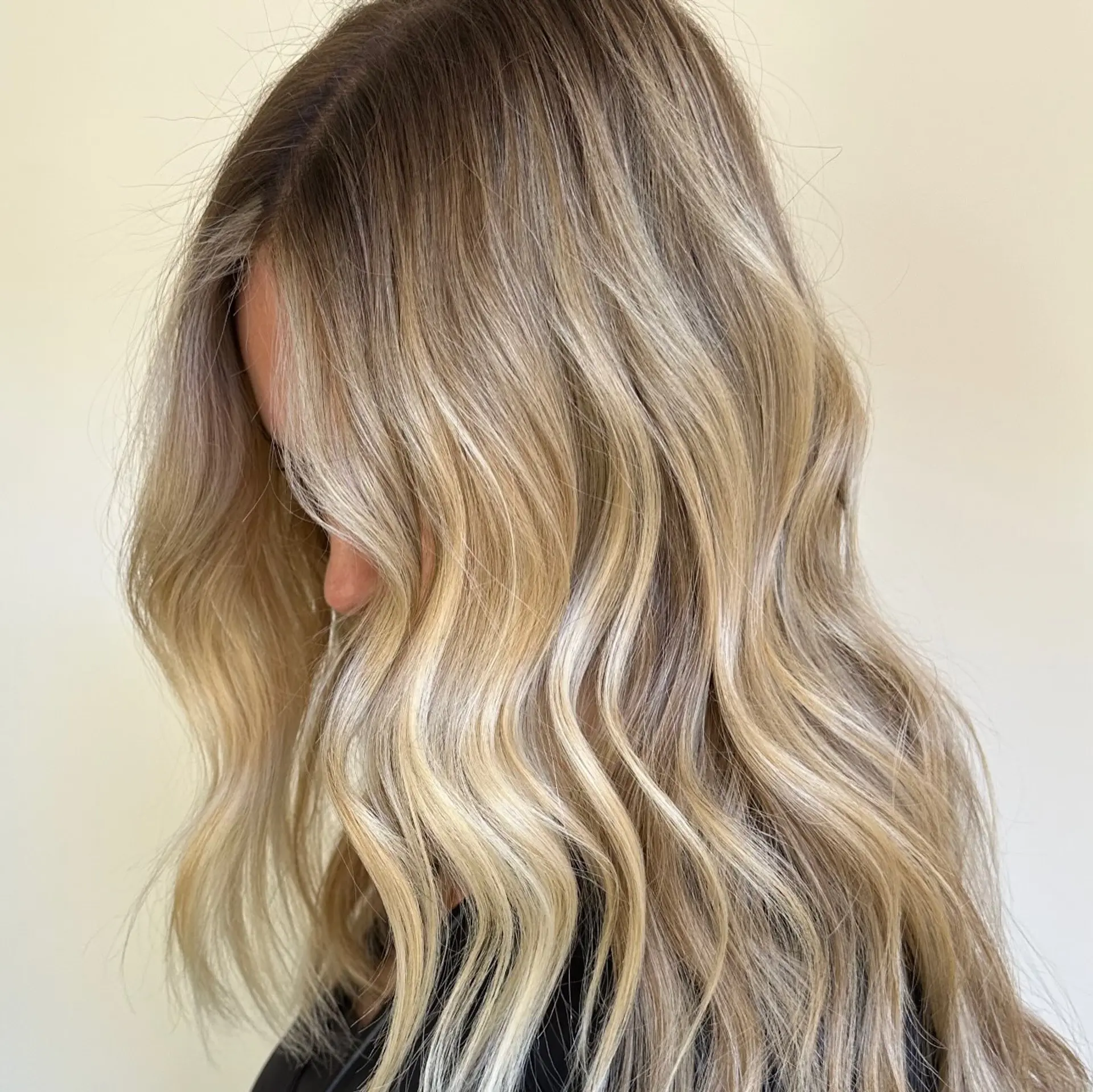 Long wavy hair featuring a seamless lived-in blonde balayage with a soft shadowed root. 1
