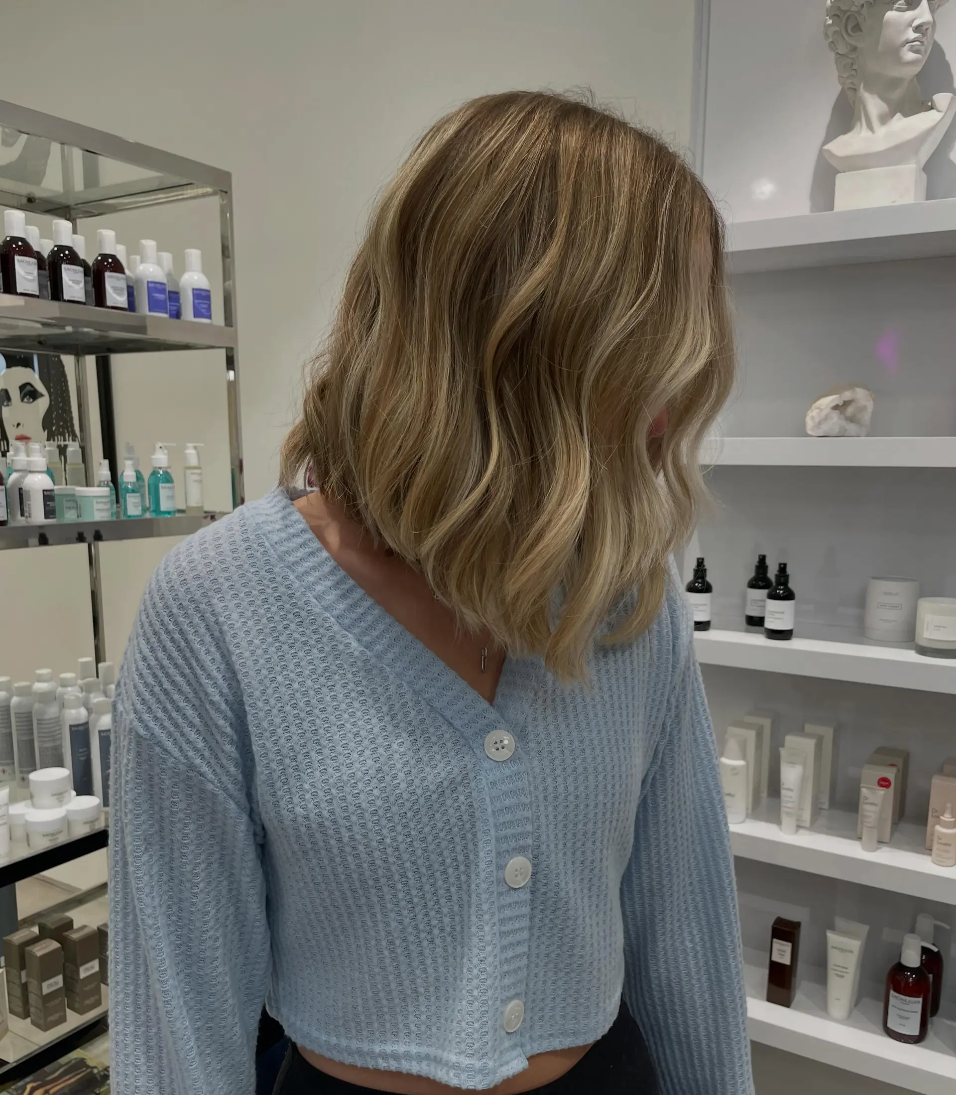 A textured, shoulder-length bob styled in effortless, loose waves with dimensional golden blonde highlights. 1