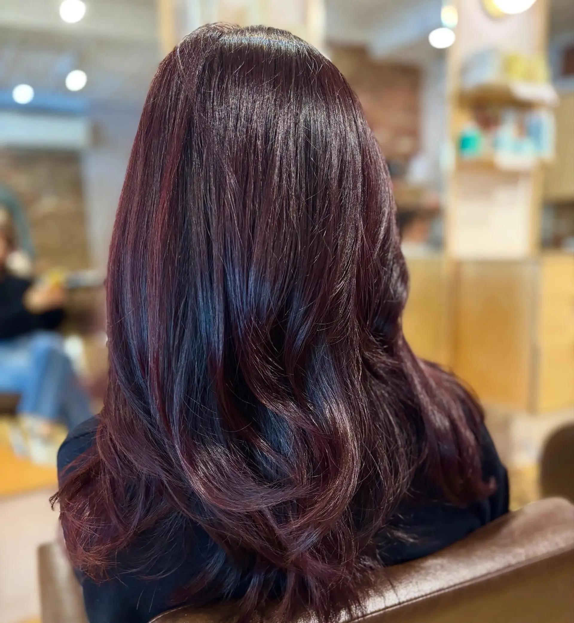 Long layered haircut styled with soft, voluminous waves and rich cherry cola burgundy hair color. 1