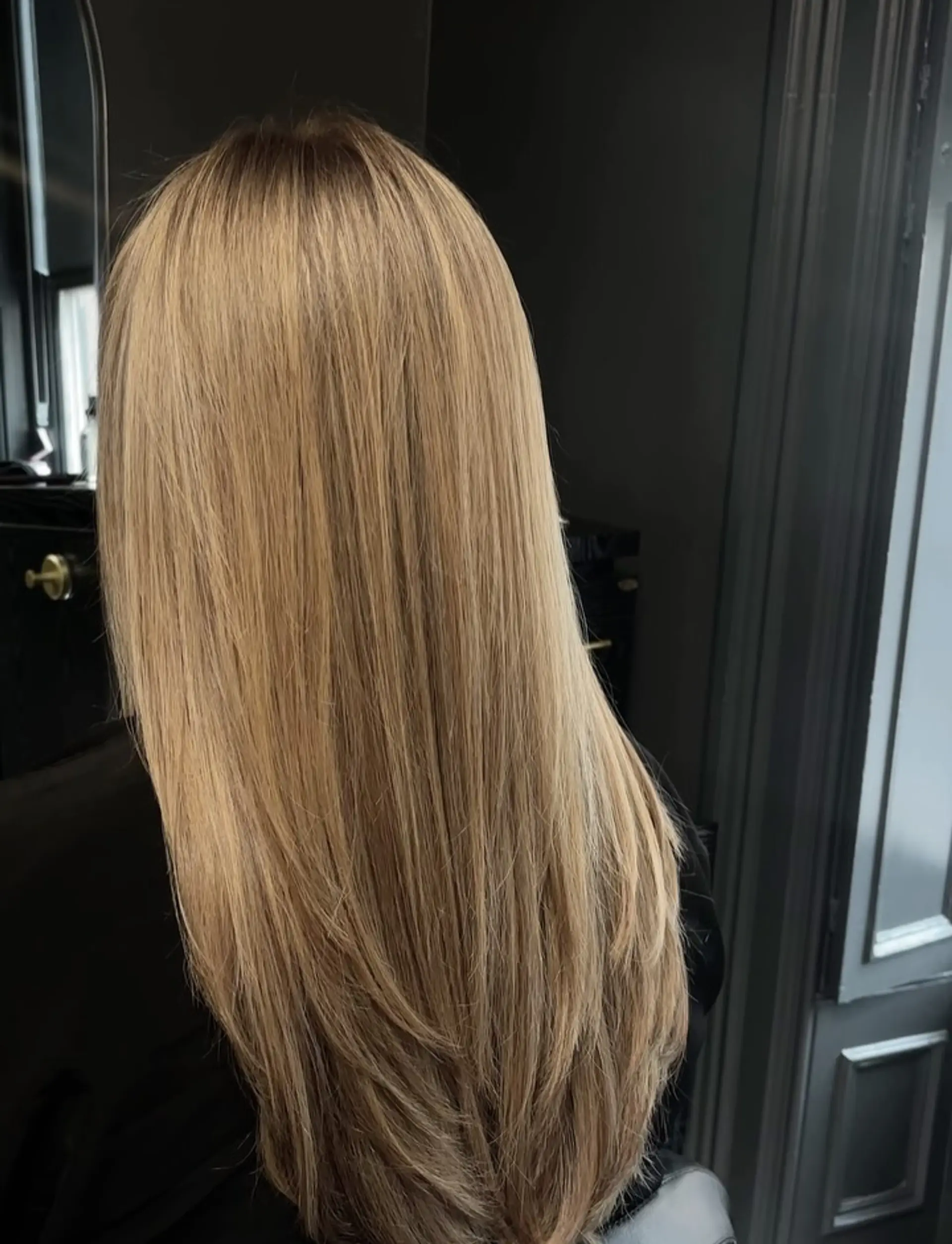 Long, sleek straight hair colored in a seamless bronde blend with soft tapered layers at the ends. 1