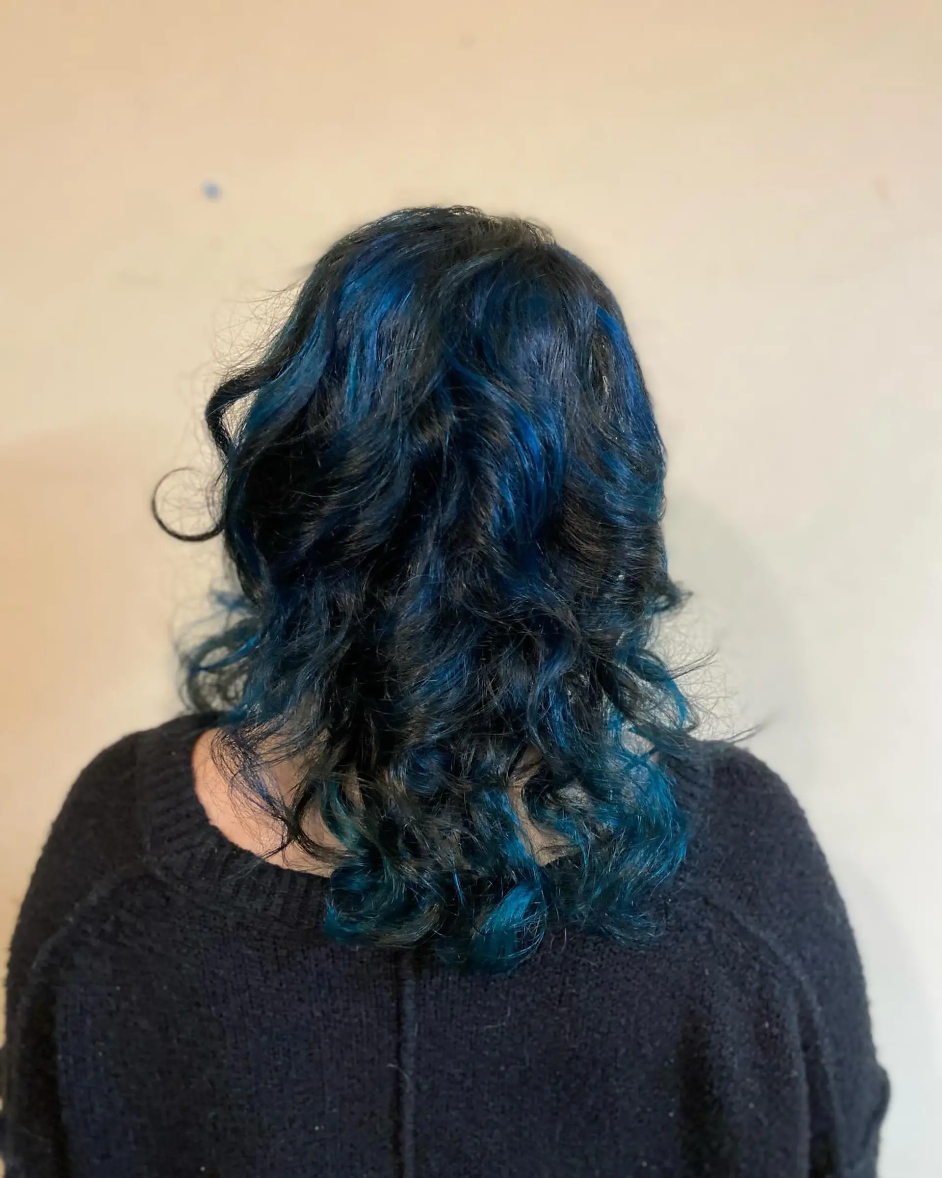 Medium-length dark hair styled in textured waves, featuring bold, chunky cobalt blue highlights woven throughout. 1