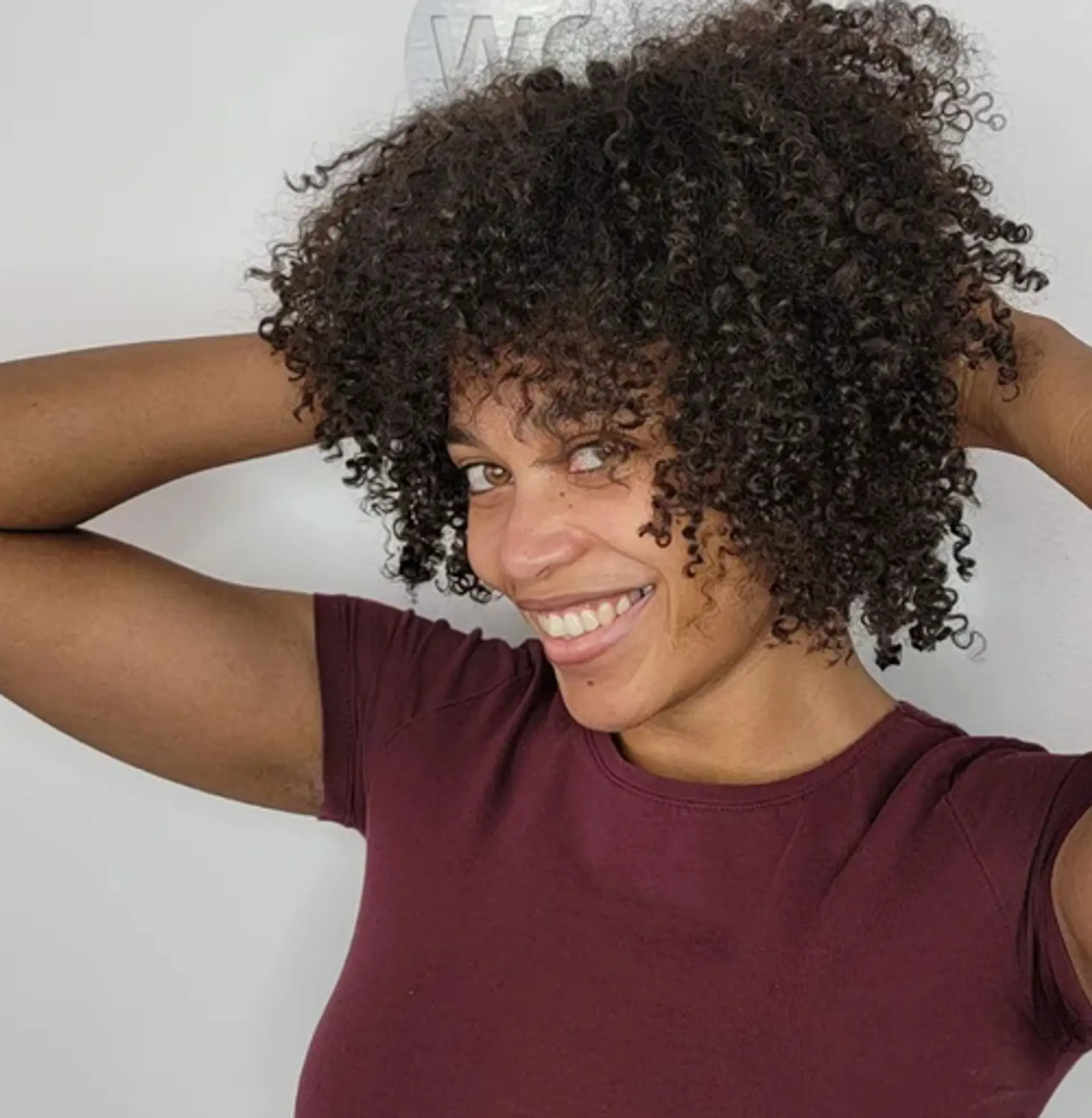 A voluminous medium-length natural afro with tight, dark brown curly hair. 1
