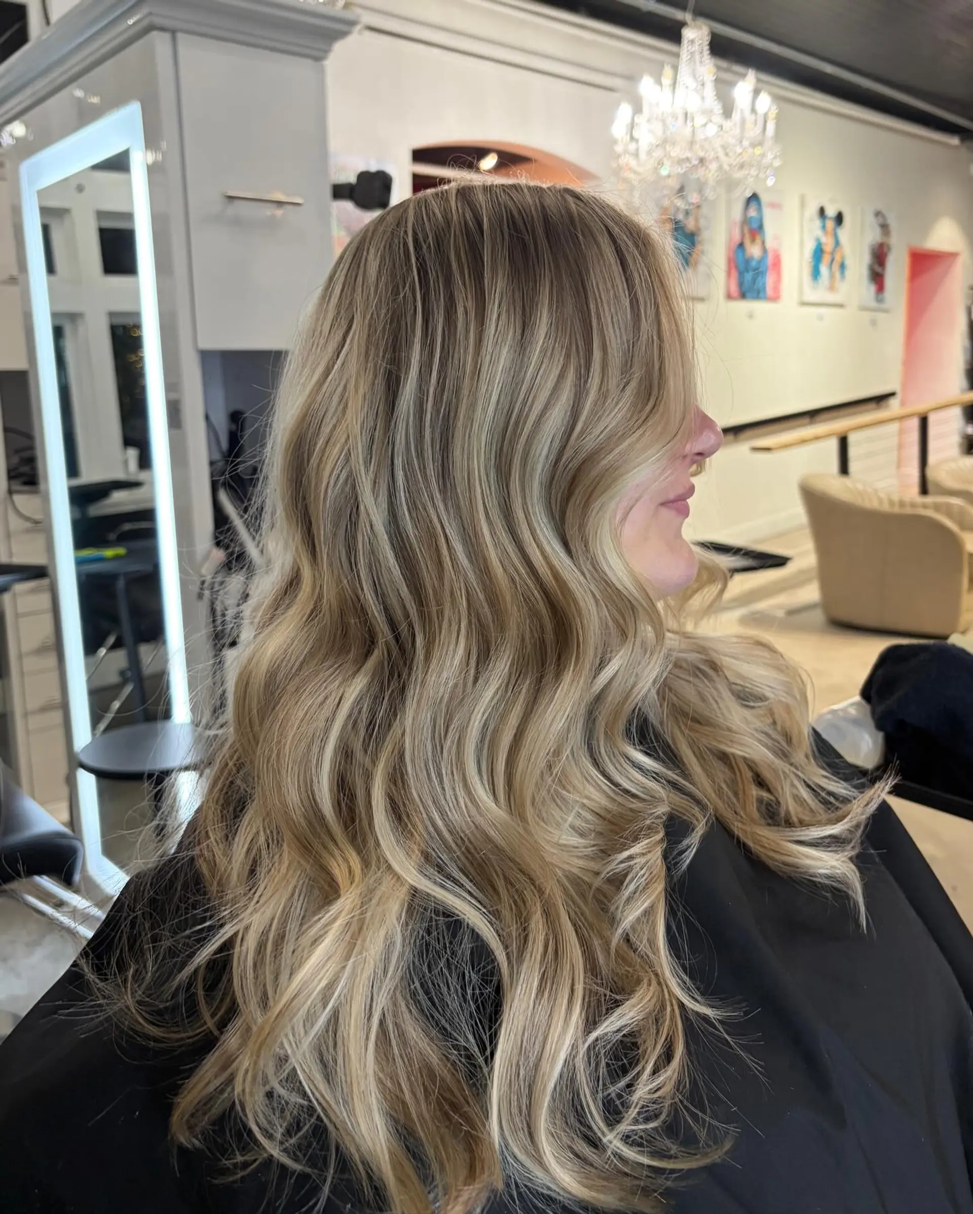 Long, multi-tonal dimensional blonde hair styled into soft, flowing beach waves. 1
