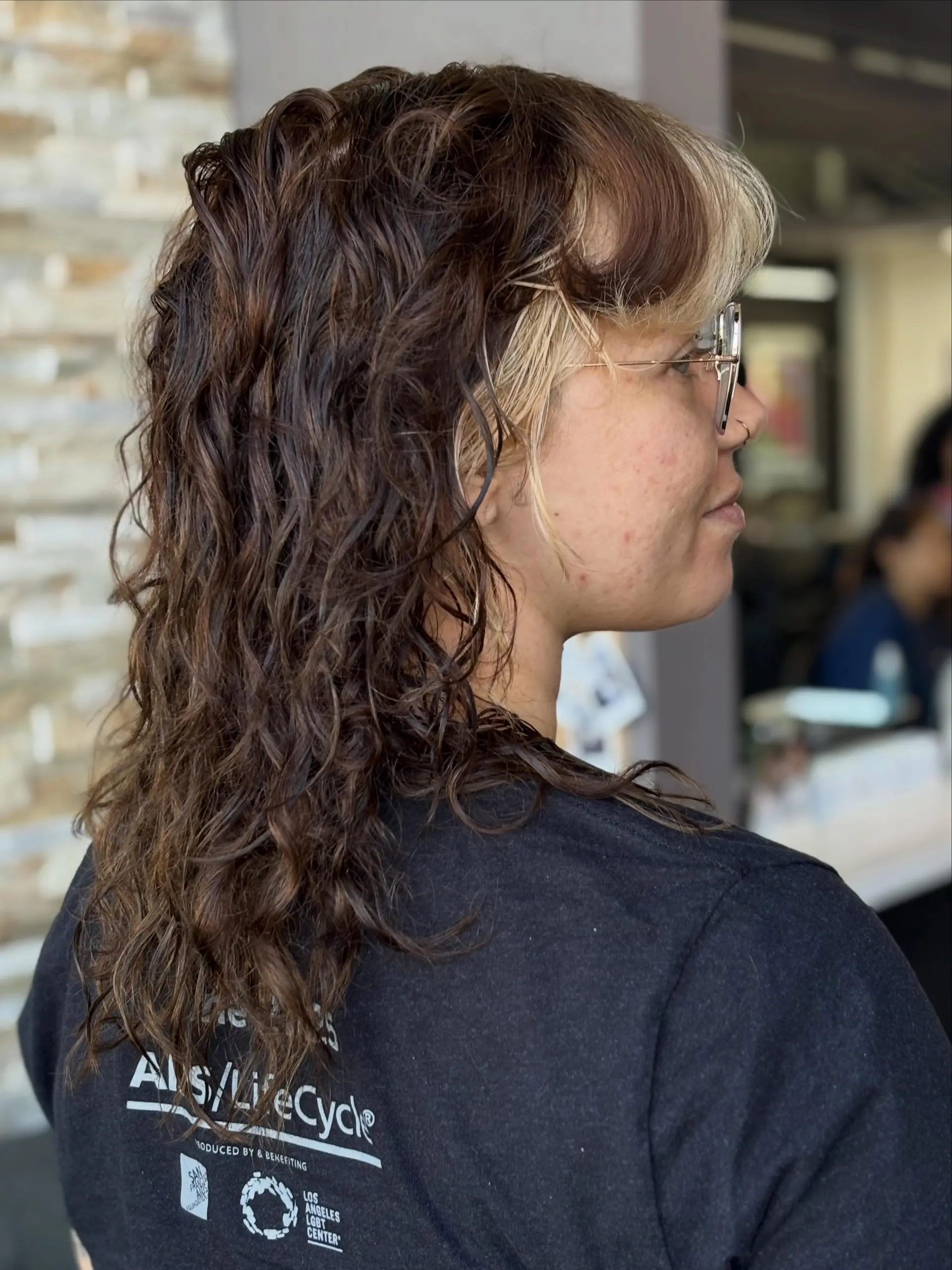 Medium-length curly shag haircut featuring textured layers and high-contrast blonde face-framing money pieces paired with a rich dark brown base. 1