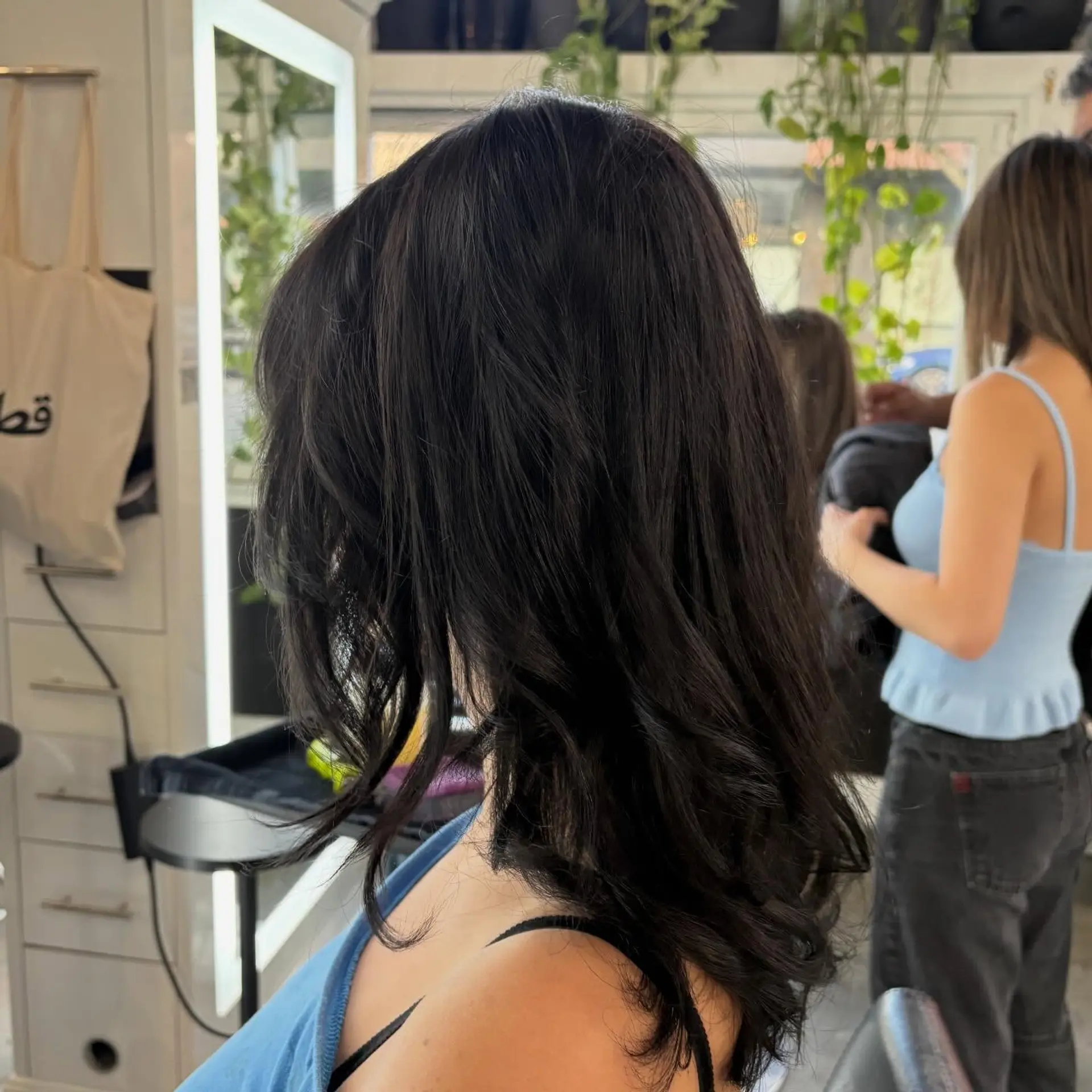 Medium-length dark hair styled in a textured, voluminous blowout with face-framing layers and soft, curved ends. 1