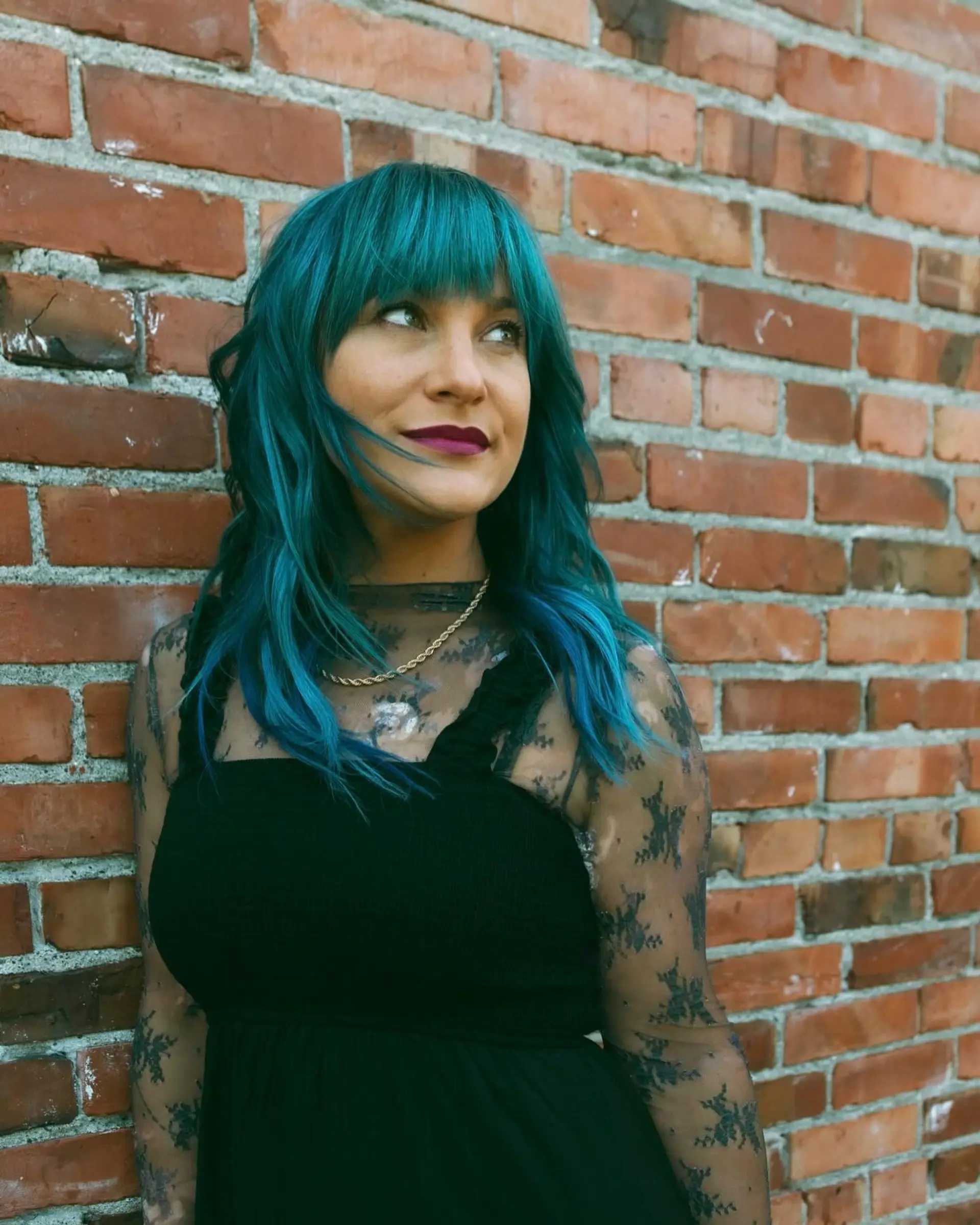 Medium-length textured waves dyed in an intense teal hue, paired with straight-across blunt bangs. 1