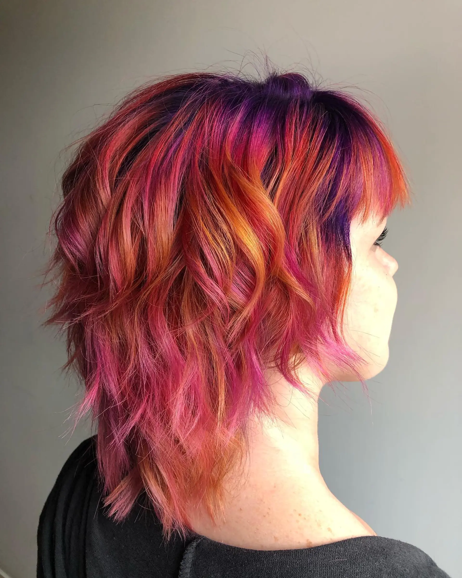 A short, shaggy pixie cut with textured layers and a bold color melt. 1