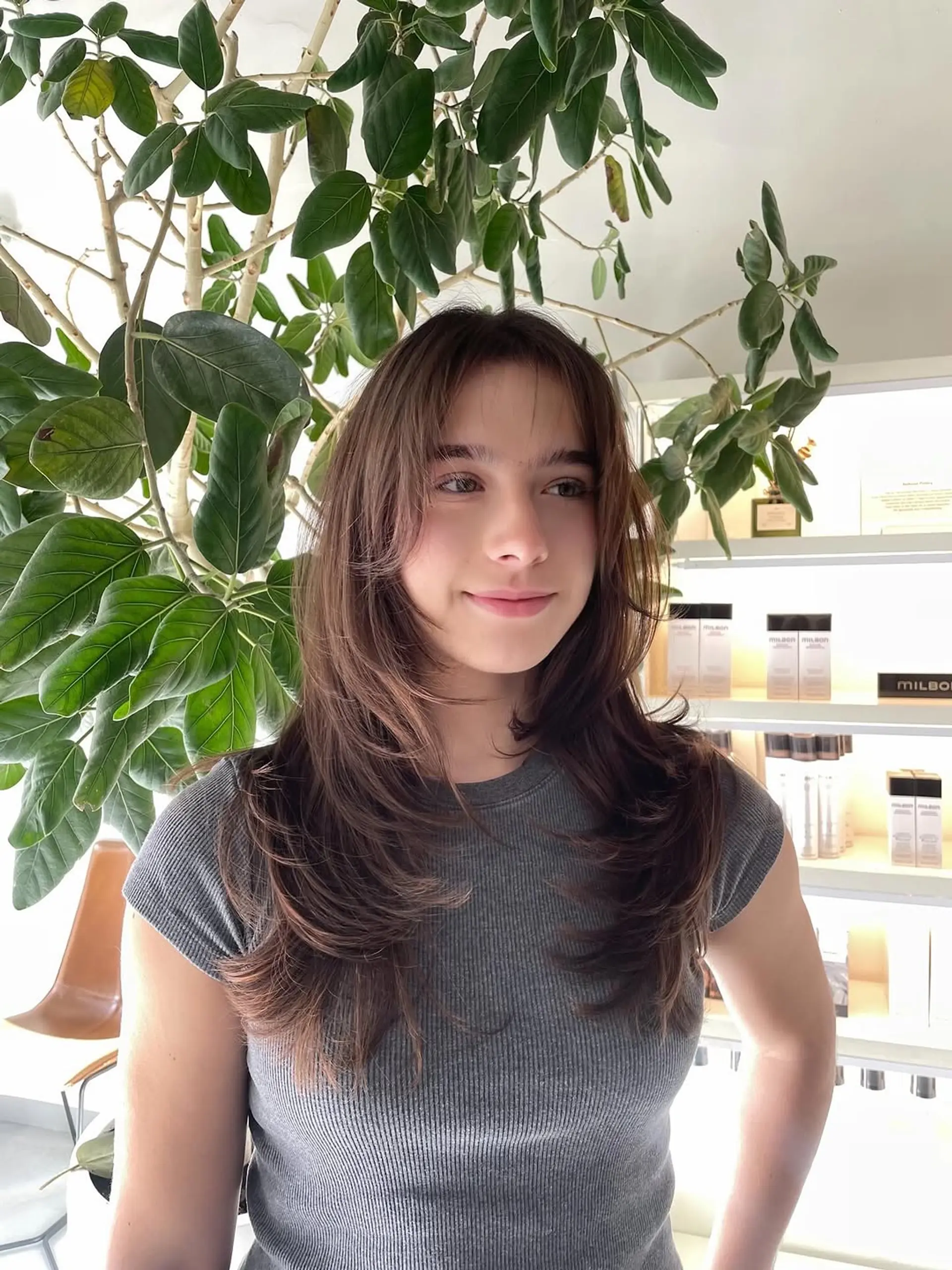 A modern long-layered haircut featuring shorter, face-framing sections that blend seamlessly into longer, cascading layers, mimicking a butterfly wing effect with soft, wispy curtain bangs. 1