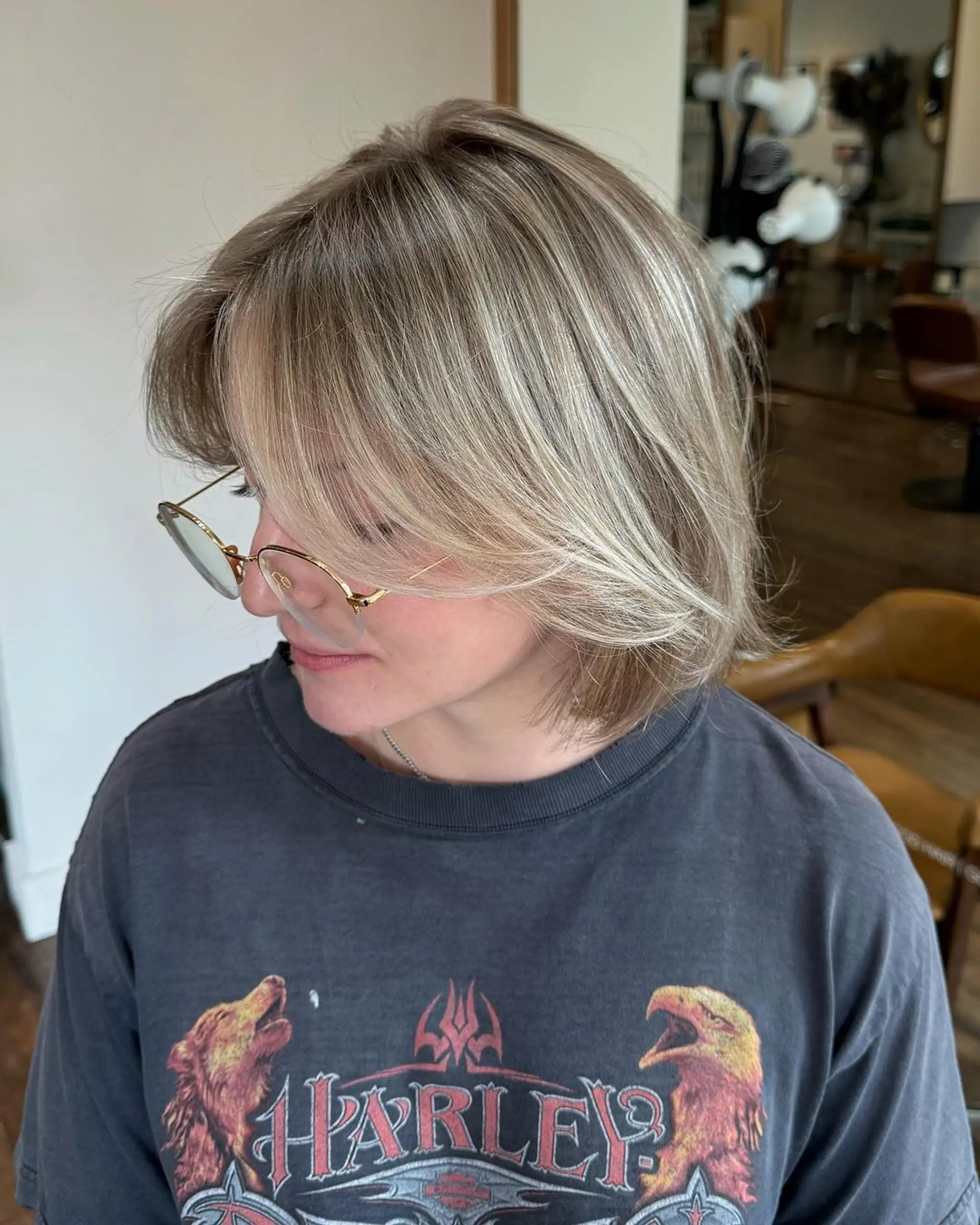 Medium-length straight bob with face-framing layers, blonde and honey tones, subtle highlights, feathery ends, and curtain bangs.