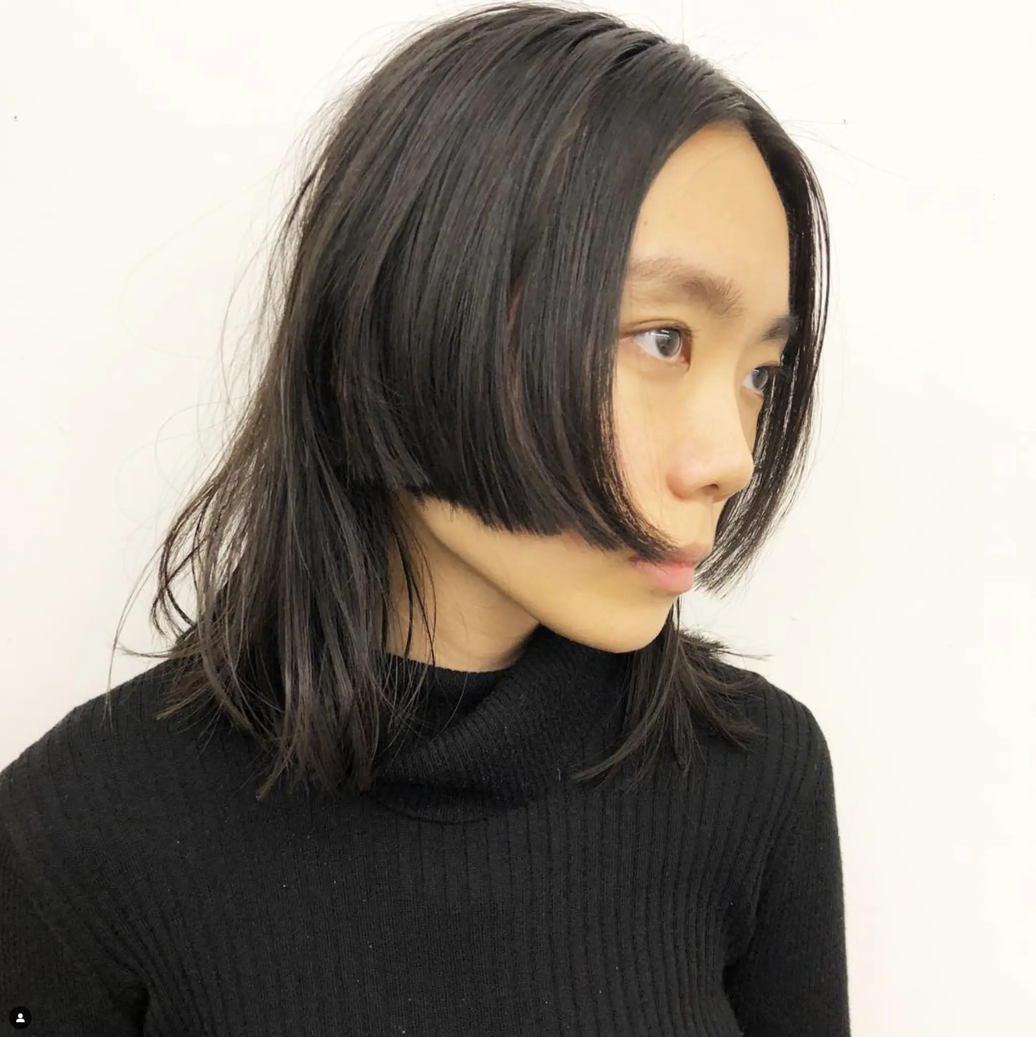 A medium-length, straight, black edgy layered bob with blunt, face-framing layers and textured ends.