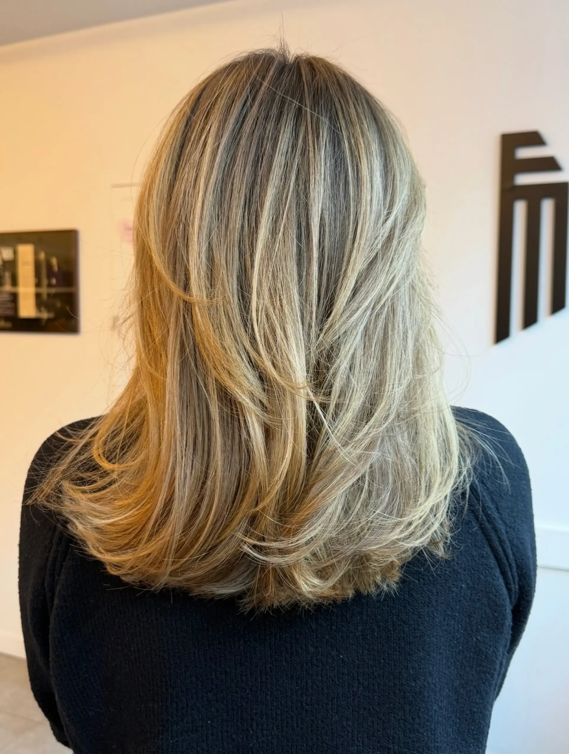 Medium-length haircut with face-framing layers and fine blonde highlights, styled smoothly with gentle movement at the ends. 1
