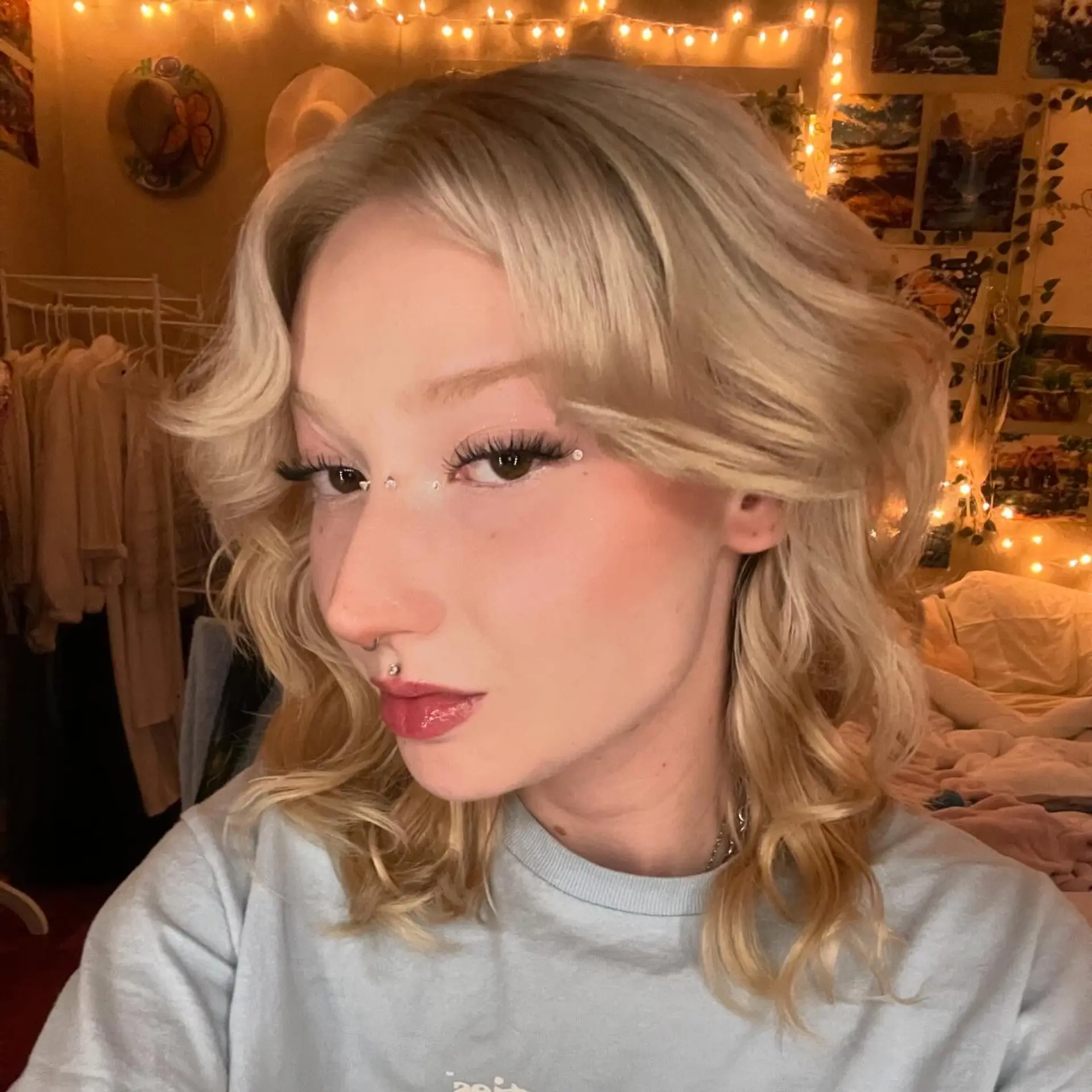 A textured shoulder-length haircut in warm blonde with sweeping retro curtain bangs and soft waves. 1