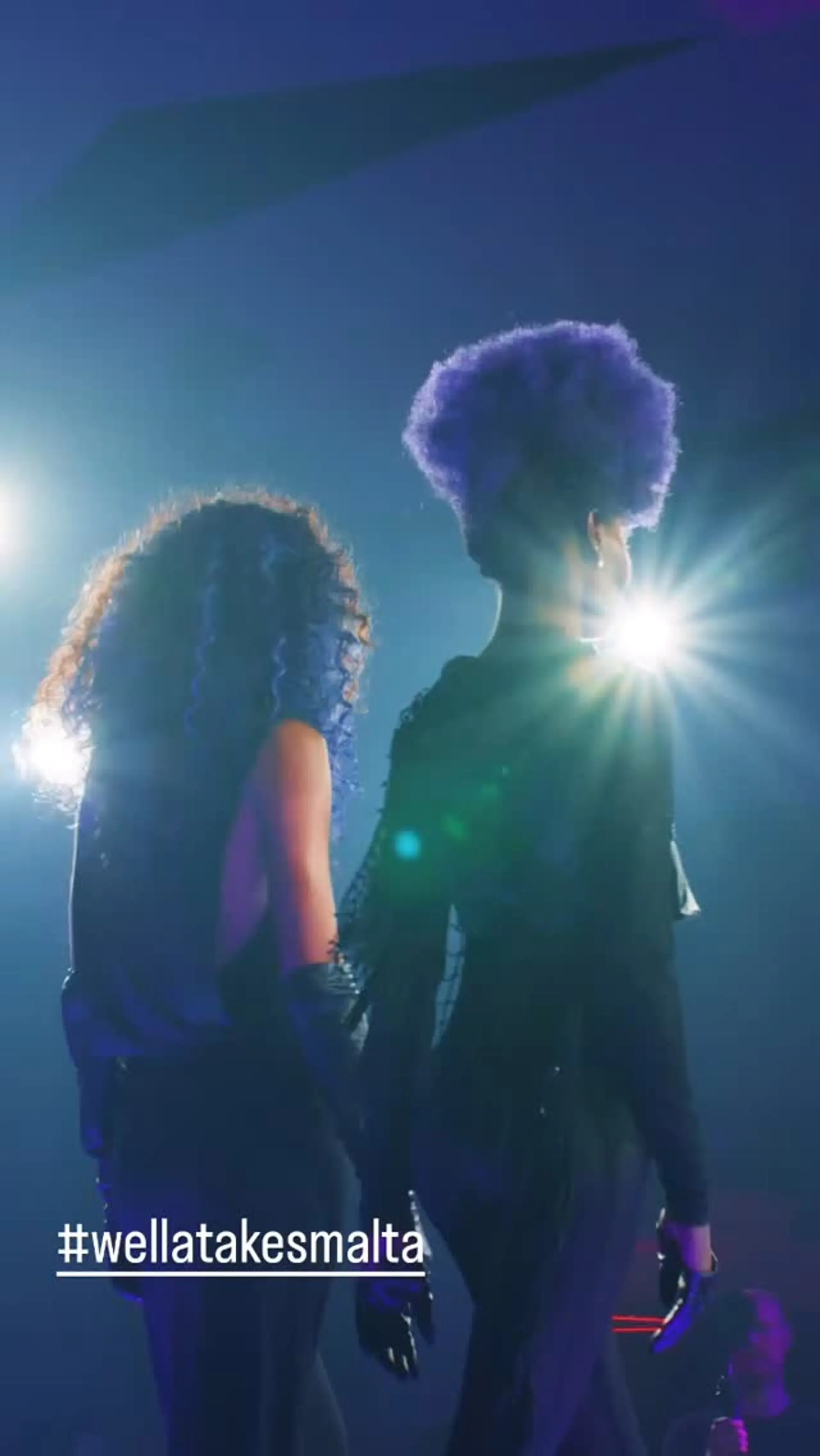 Two models showcasing vibrant, bold fashion-colored hair in a stage lighting setting. 1
