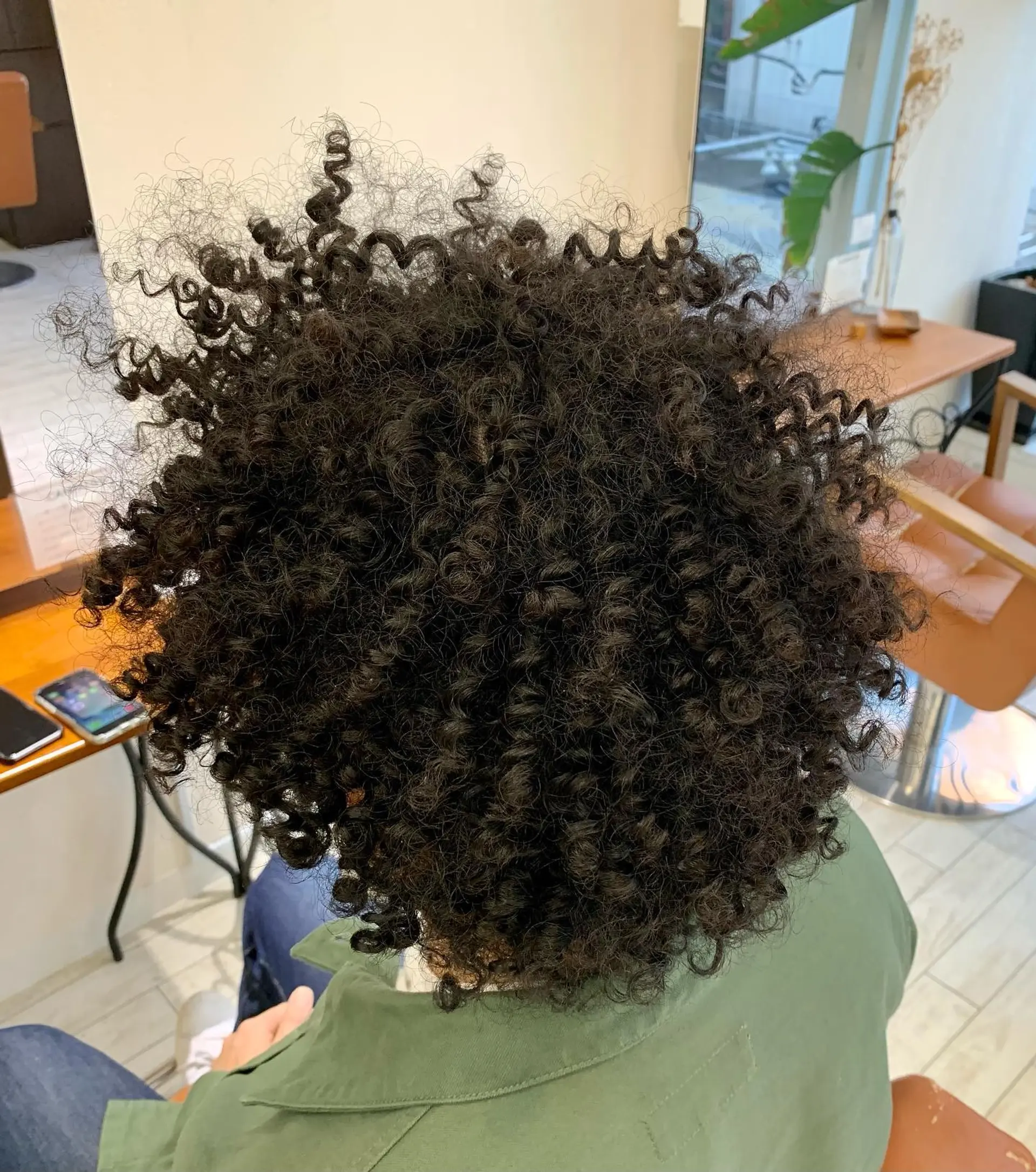 A full, voluminous afro haircut featuring tightly defined spiral ringlets and texture throughout. 1